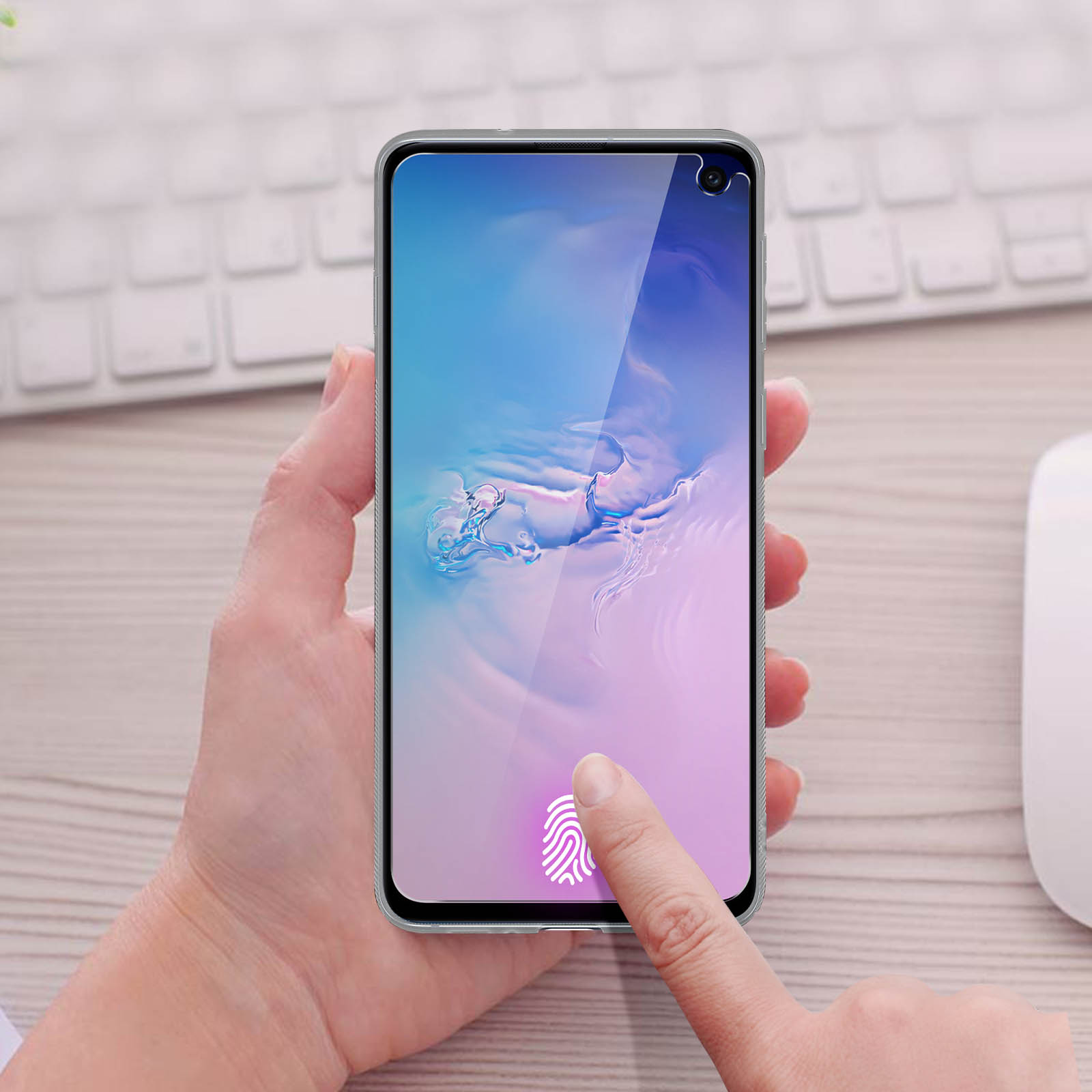 Mano che tiene un telefono, dito che tocca lo schermo con impronta digitale. Tastiera e mouse sullo sfondo.