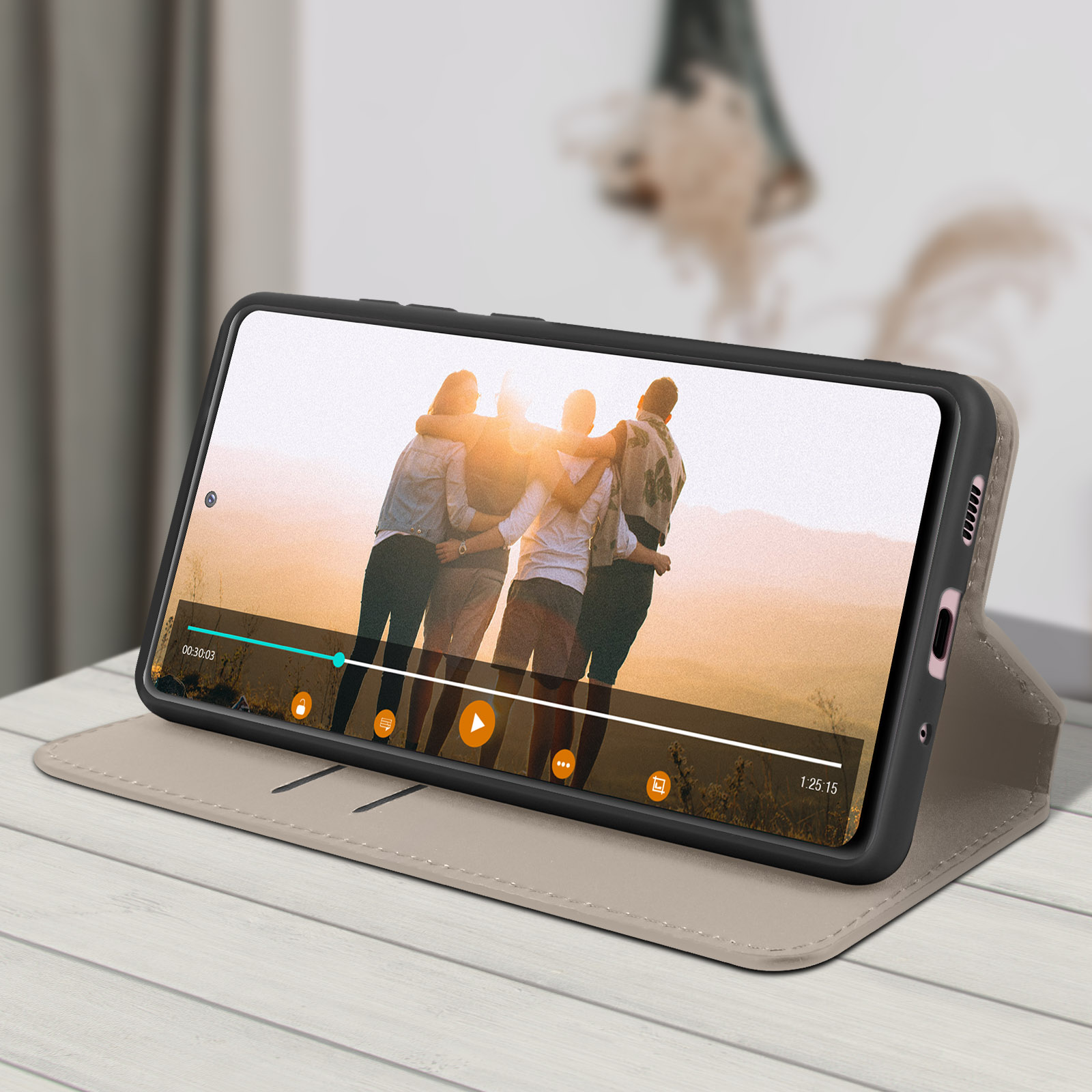 Ein Telefon in einer Hülle zeigt ein Video. Es liegt auf einem Holztisch, mit verschwommenem Hintergrund eines Wohnzimmers.