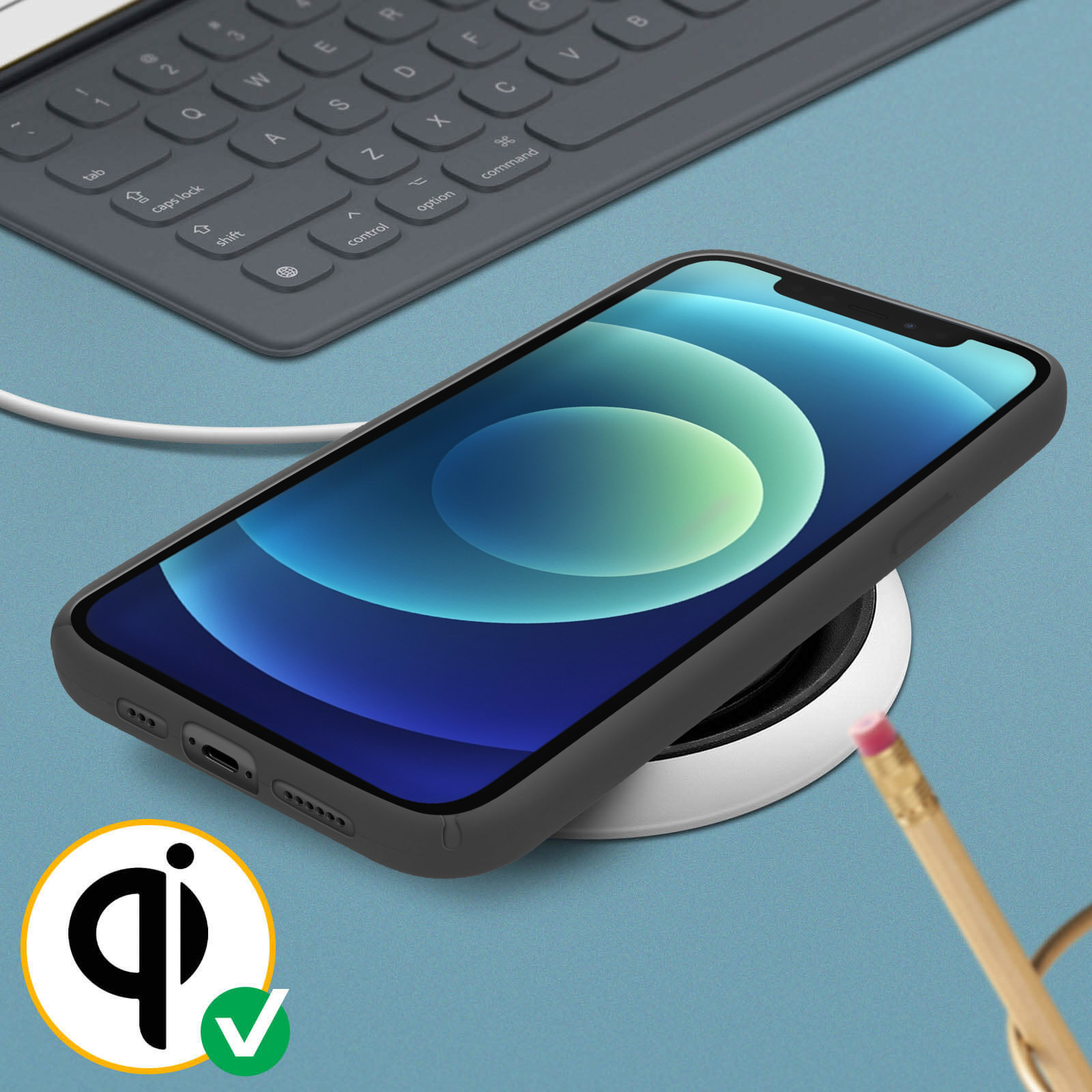Téléphone sur un chargeur sans fil avec un crayon et un clavier.