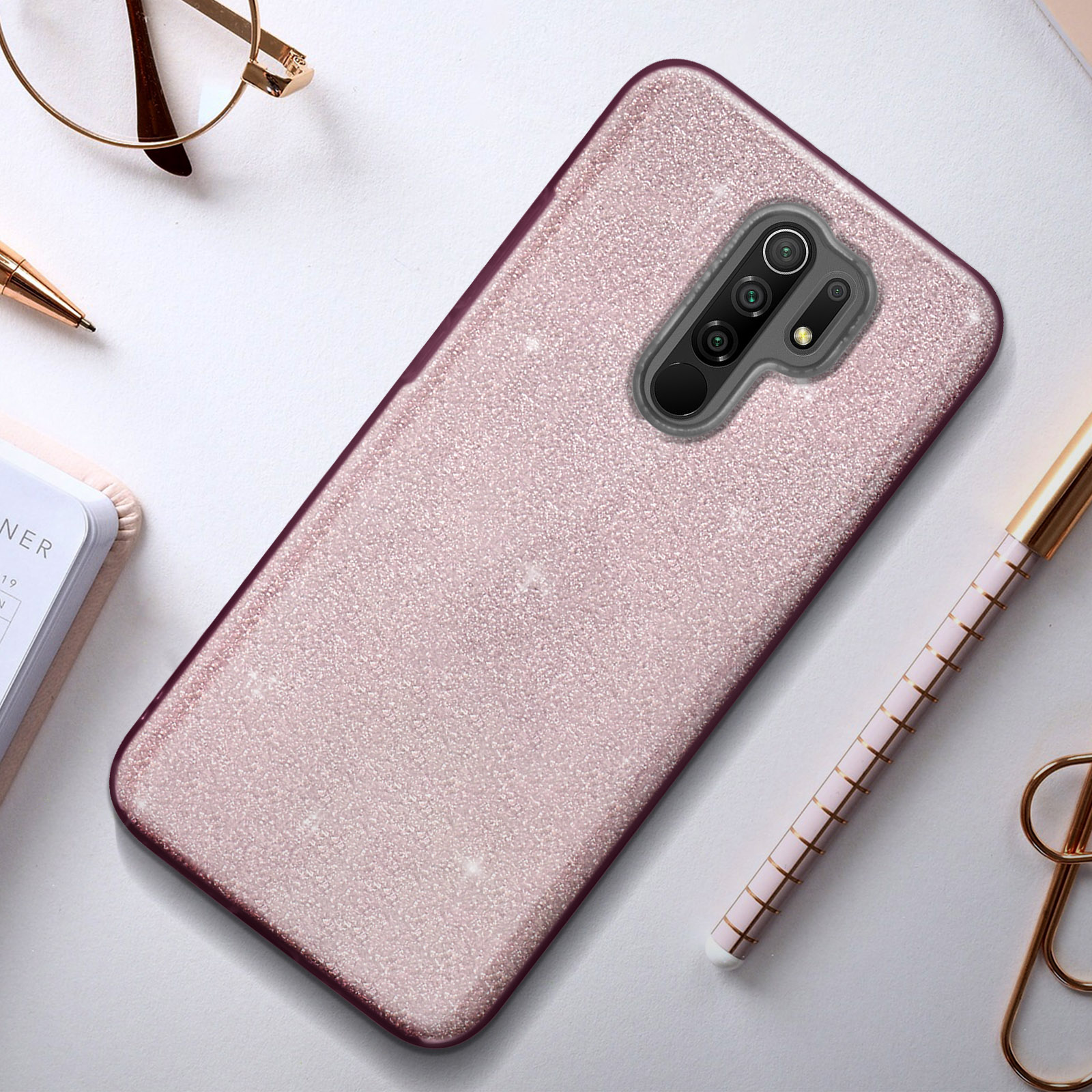 Roze glitter telefoonhoesje met pennen en bril.