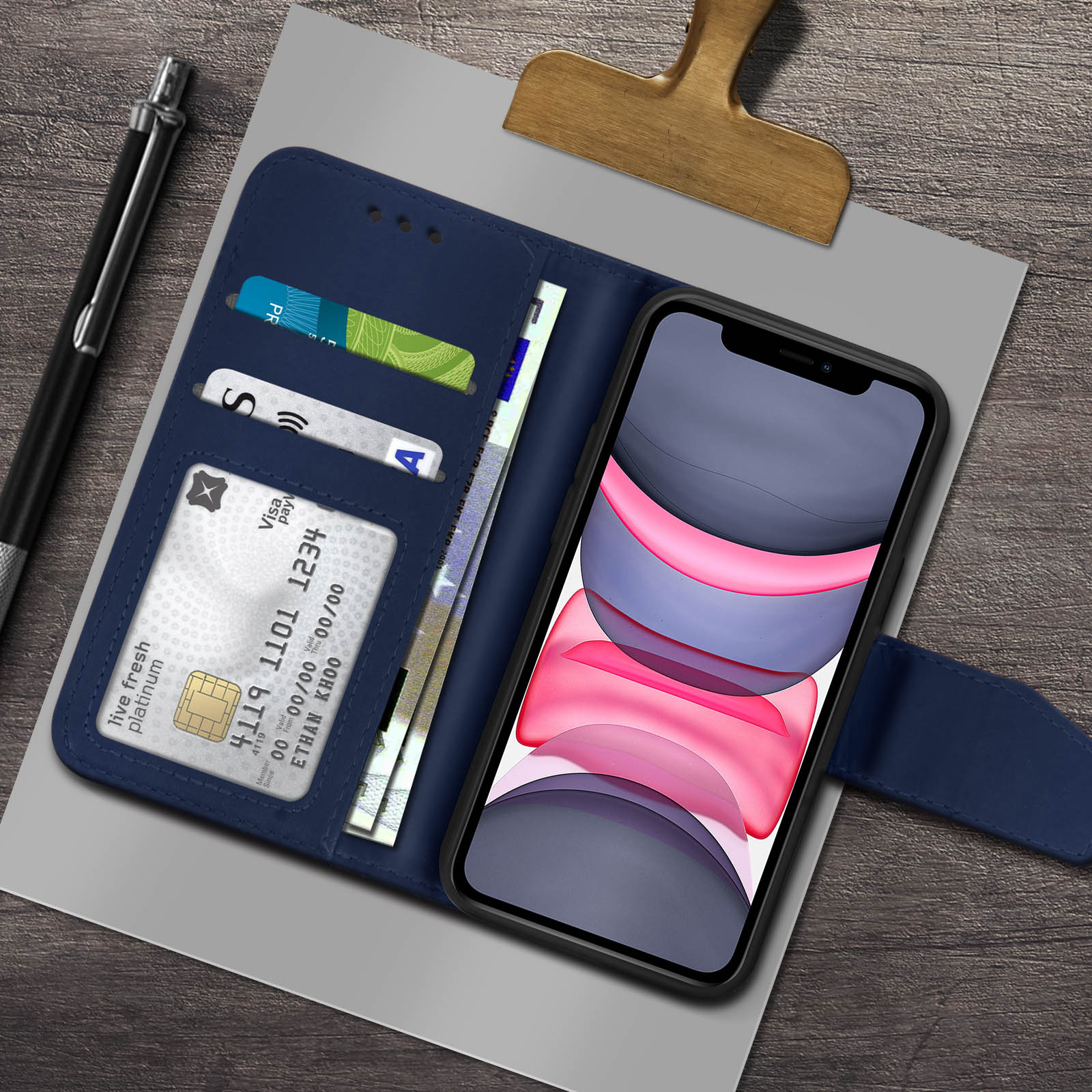 Un telefono in una custodia a portafoglio blu con carte di credito e denaro. Una penna a lato.