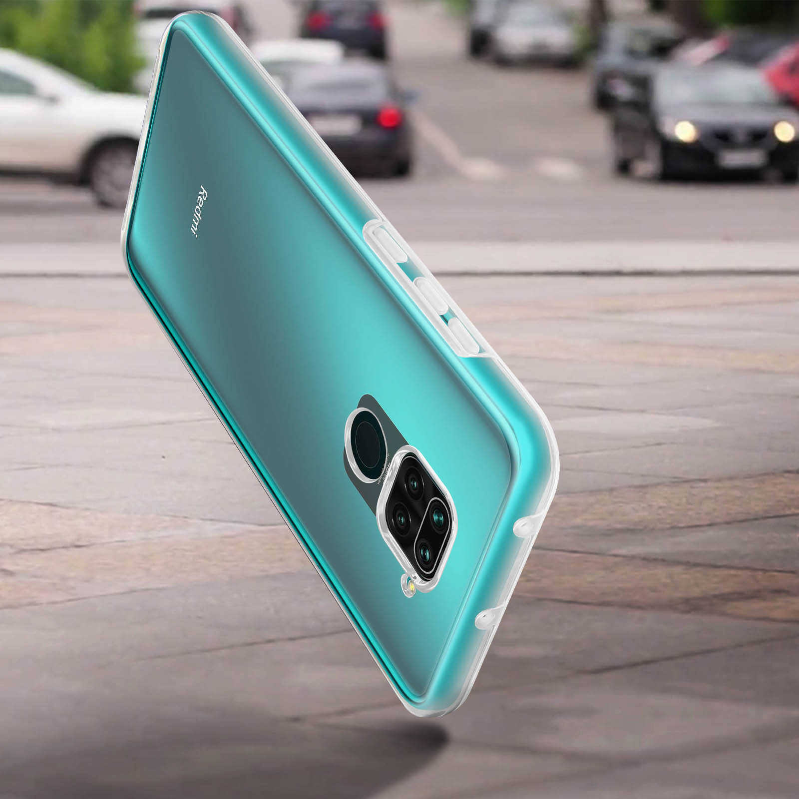 Un téléphone turquoise dans un étui transparent est incliné sur un trottoir. Les voitures sont floues en arrière-plan.