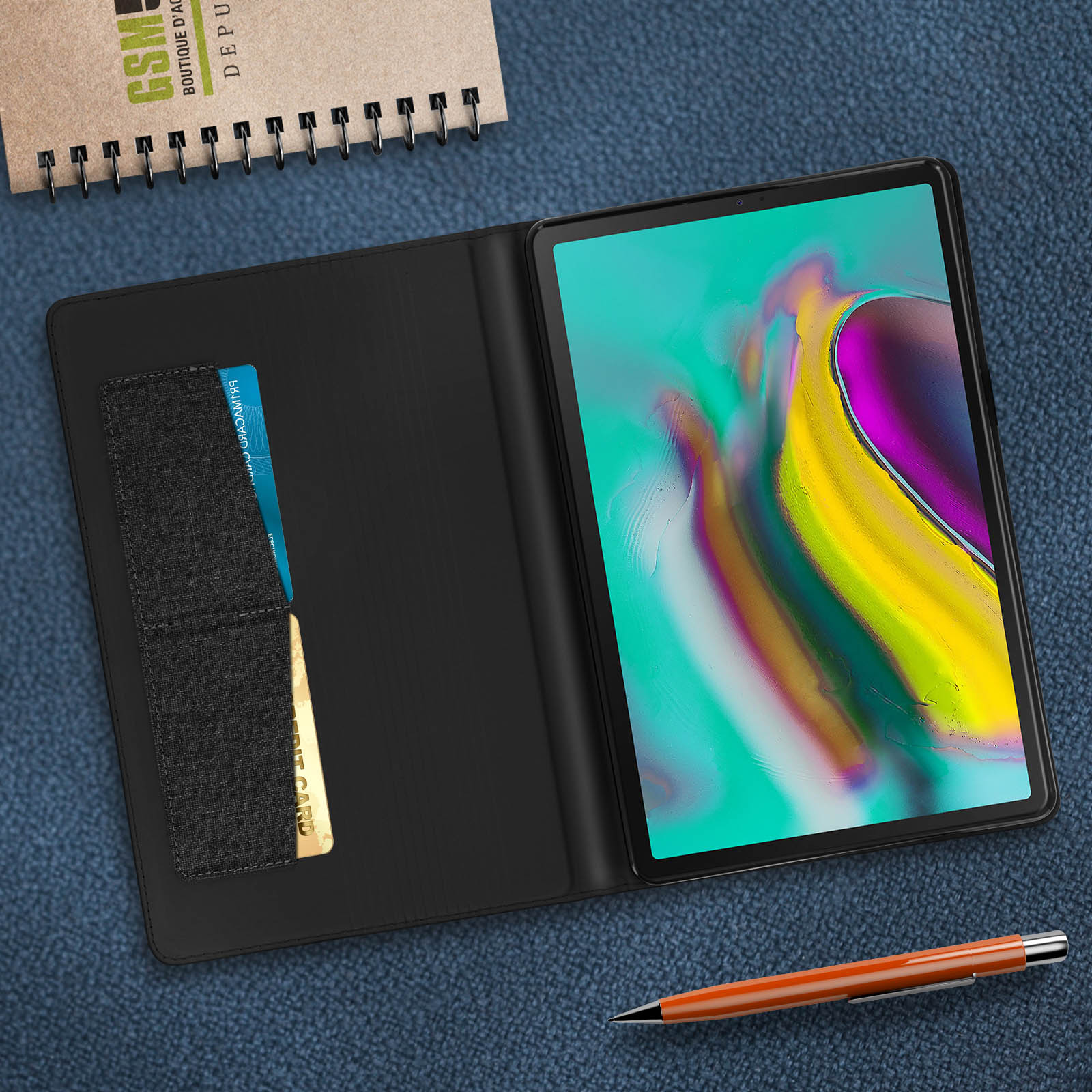 Tablet nero in una custodia nera con carta di credito dorata su superficie blu.