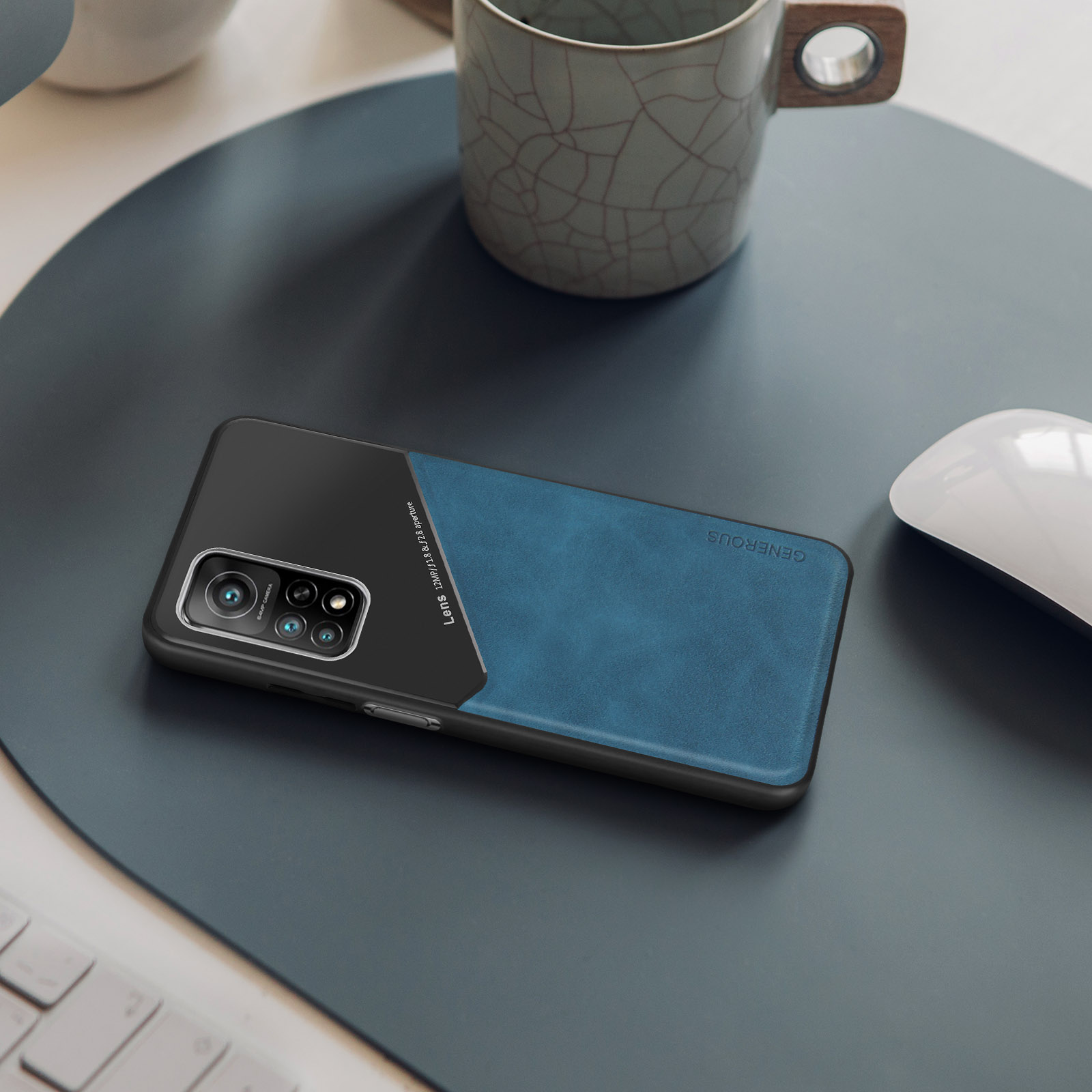 Telefono nero in una custodia blu e nera. Mouse e tazza sullo sfondo.
