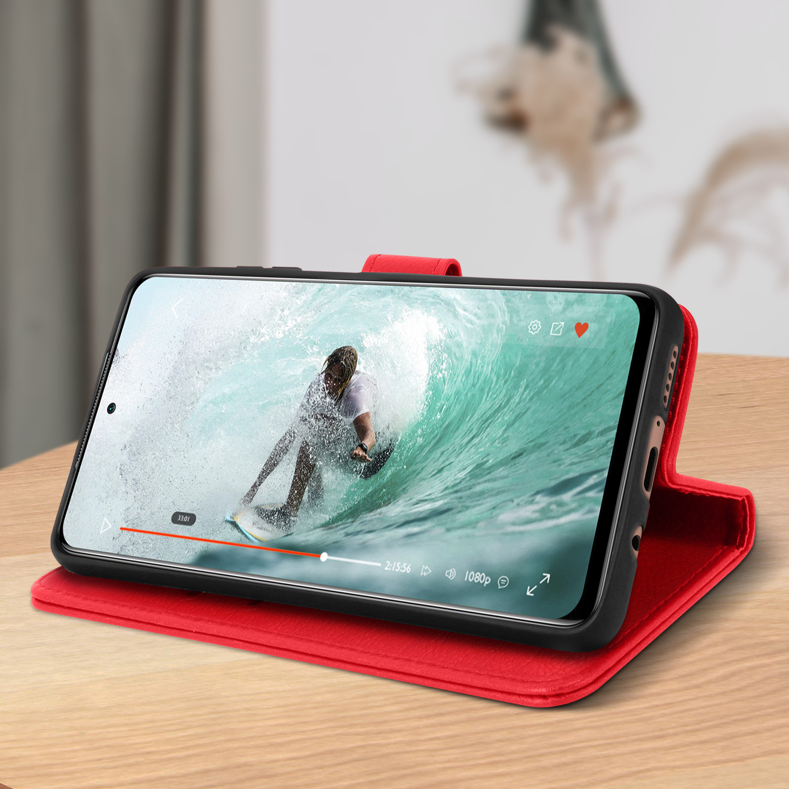 Telefono in custodia rossa, riproduce un video di un surfista su un'onda.