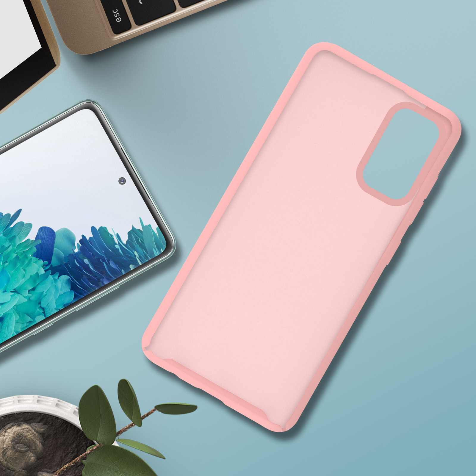 Roze telefoonhoesje op blauw oppervlak. Telefoon en plant op de achtergrond.