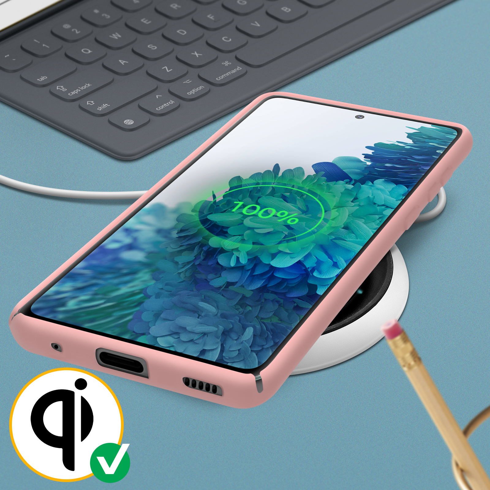 Roze telefoon in een roze hoesje op een draadloze oplader, met een toetsenbord en potlood.