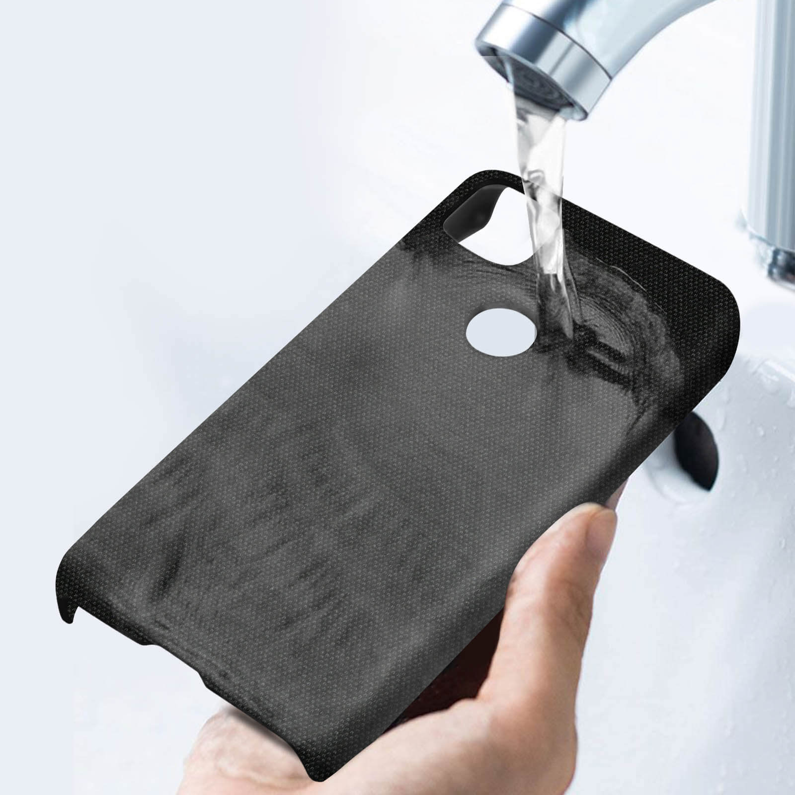 De l'eau est versée sur une coque de téléphone noire dans un évier. Une main tient la coque.