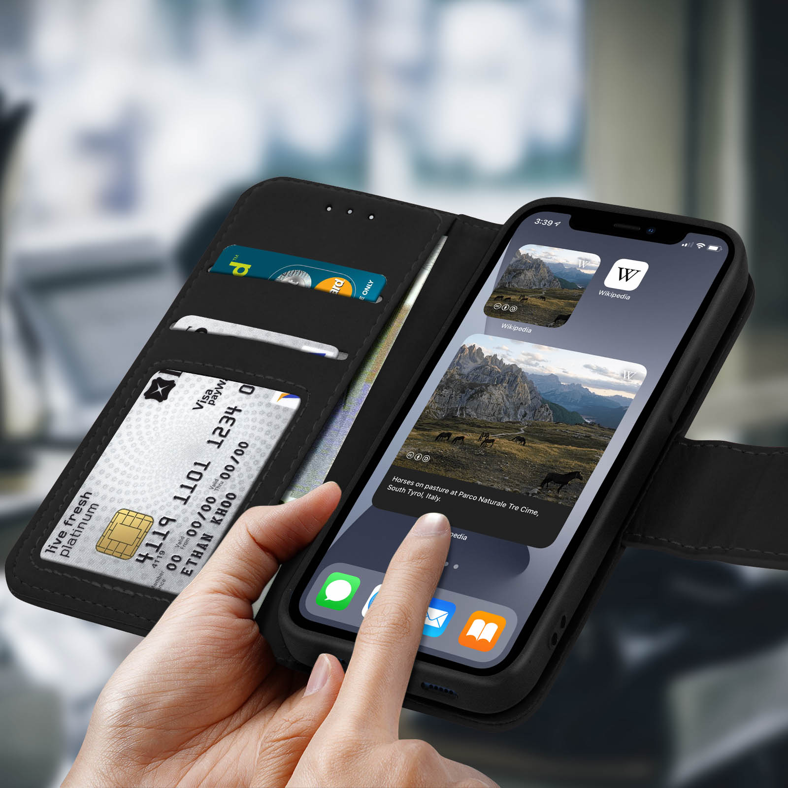 Telefono in una custodia a portafoglio nera. Carte di credito visibili nella sezione portafoglio, schermo mostra app.