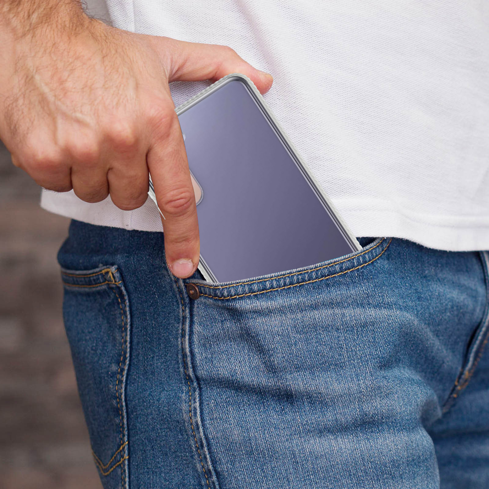 Ręka wkłada telefon w etui do kieszeni dżinsów.