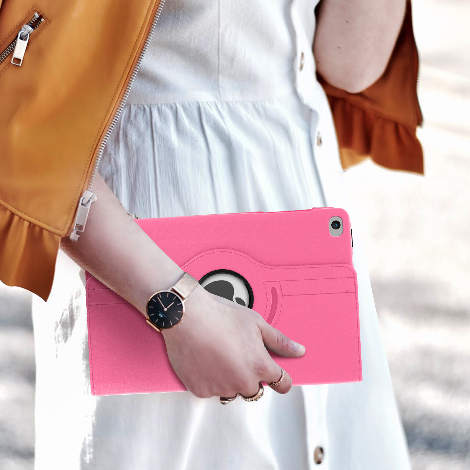 Una persona che tiene una custodia rosa per tablet, con un orologio al polso. Lo sfondo è sfocato.