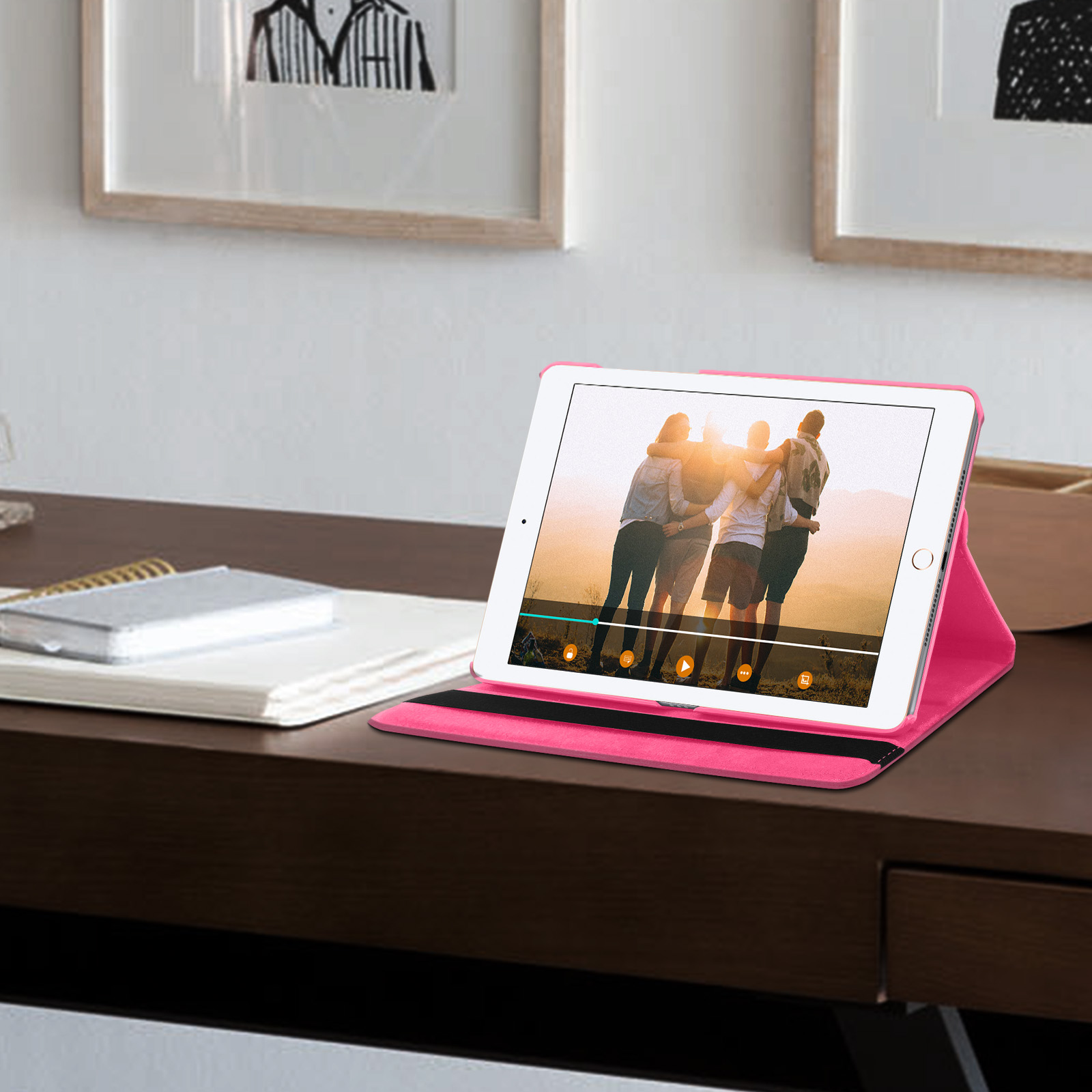 Tablet su una custodia rosa, che mostra un video. Due immagini incorniciate sono sullo sfondo.