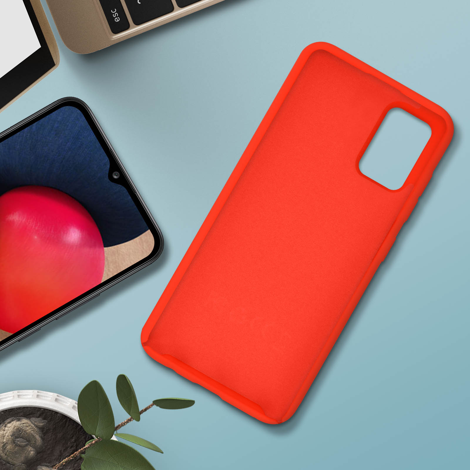 Una custodia arancione per telefono su una superficie blu con uno schermo del telefono e una pianta.