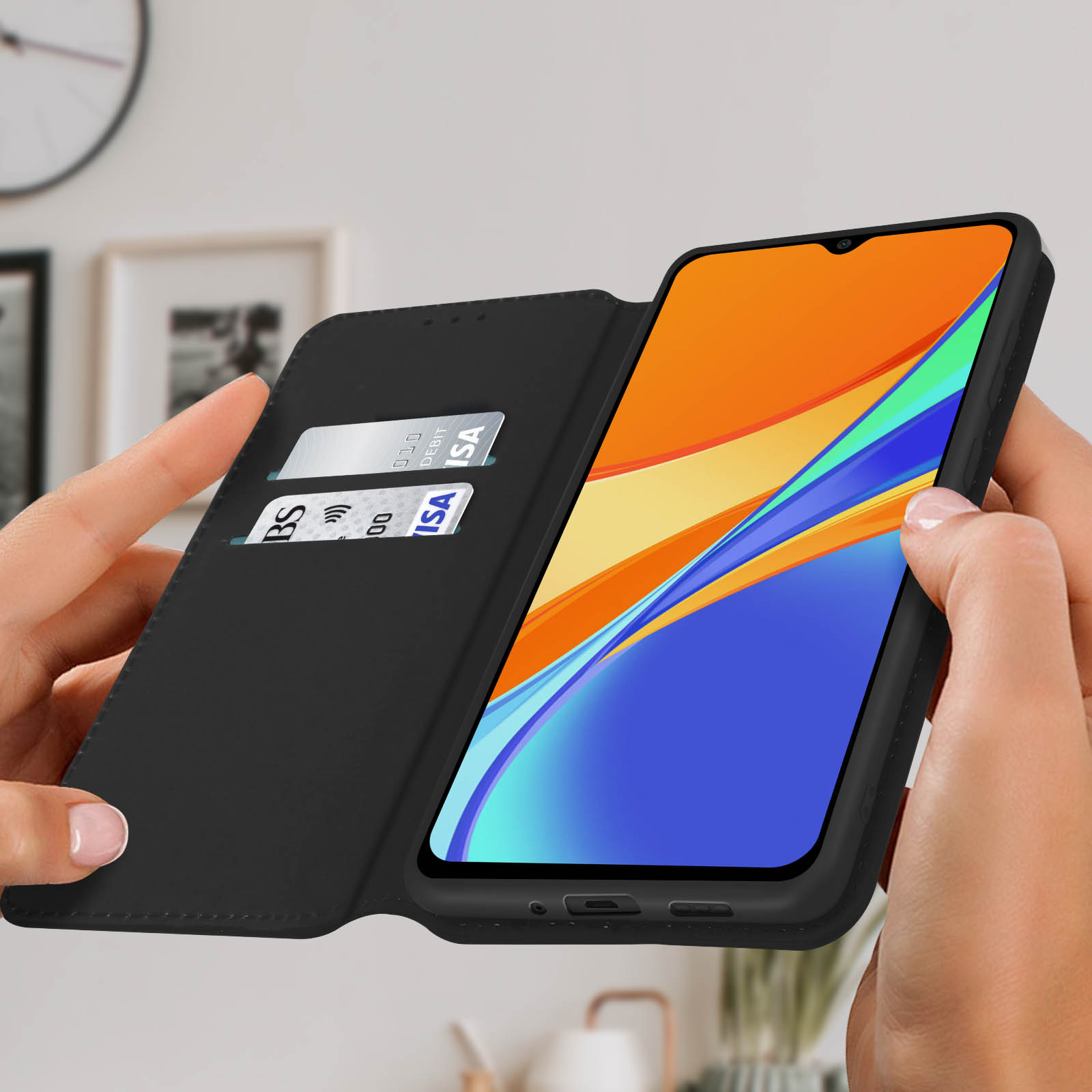 Telefoon in hoes met creditcards in sleuven, vastgehouden door handen, met een oranje en blauw scherm.