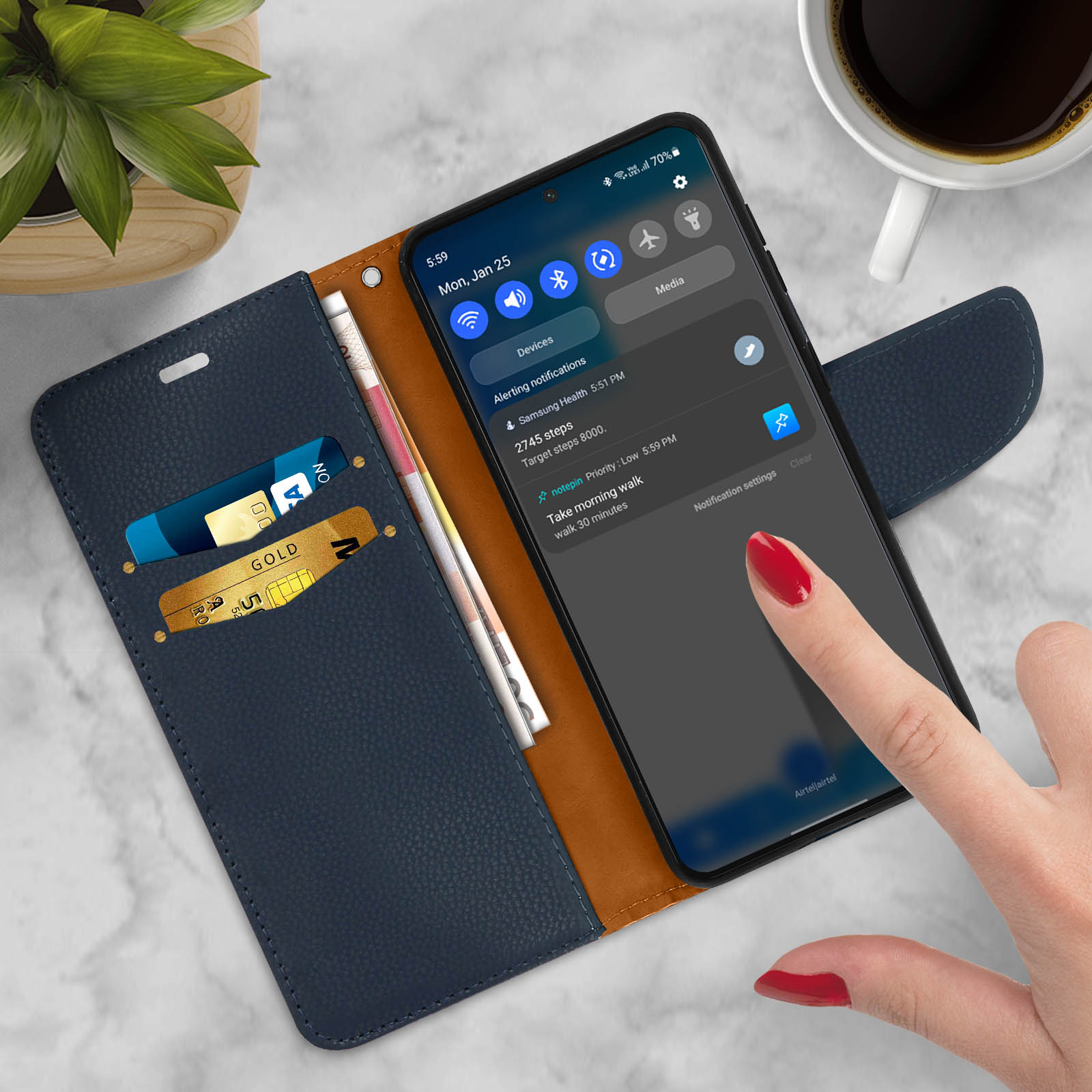 Telefono in una custodia a portafoglio blu, aperta, con carte e contanti visibili. Un dito tocca lo schermo.