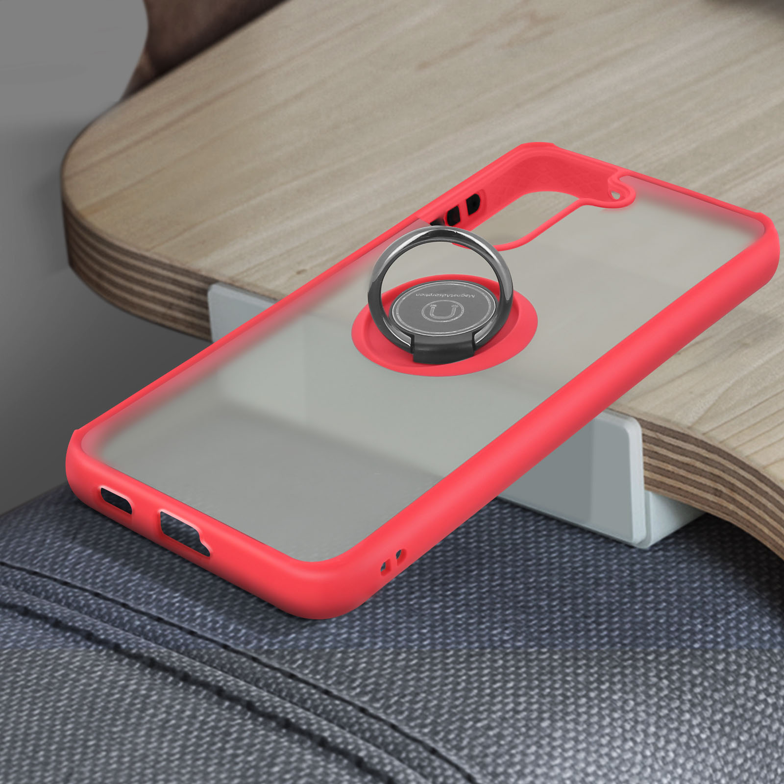 Un téléphone dans un étui rouge avec un support d'anneau. Le téléphone est sur une surface en bois et grise.