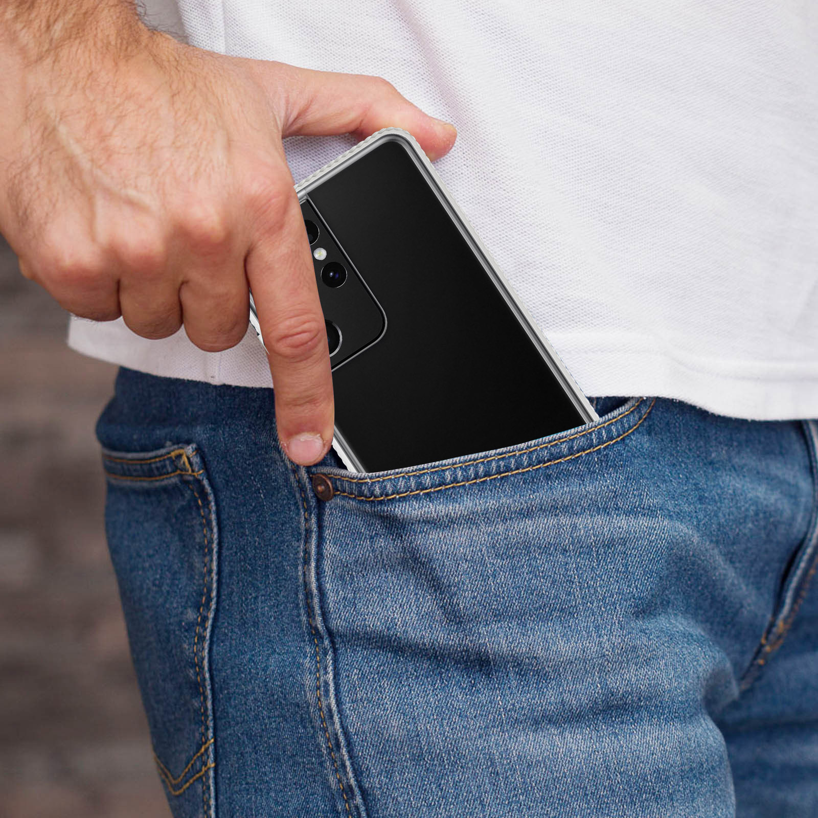 Une main met un téléphone noir dans une poche de jean bleu.