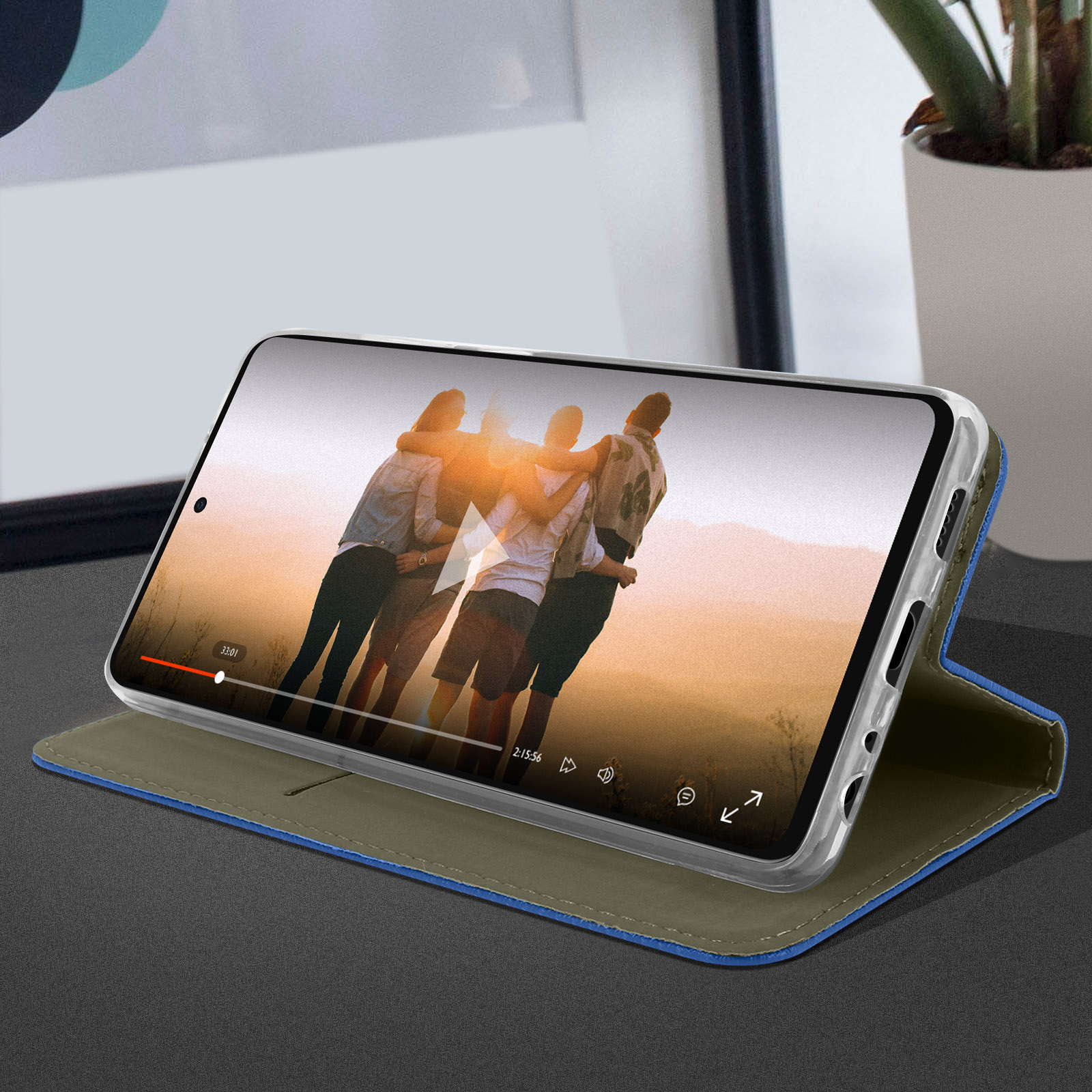 Telefon in blauem Gehäuse. Auf dem Bildschirm wird ein Video abgespielt. Eine Gruppe von Freunden umarmt sich.