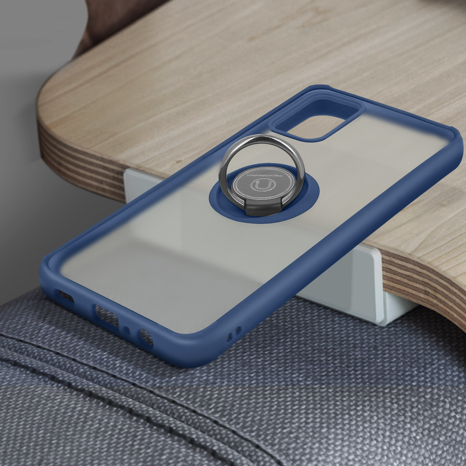 Una custodia blu per telefono con un supporto ad anello argentato è su una superficie di legno, sopra un tessuto grigio.