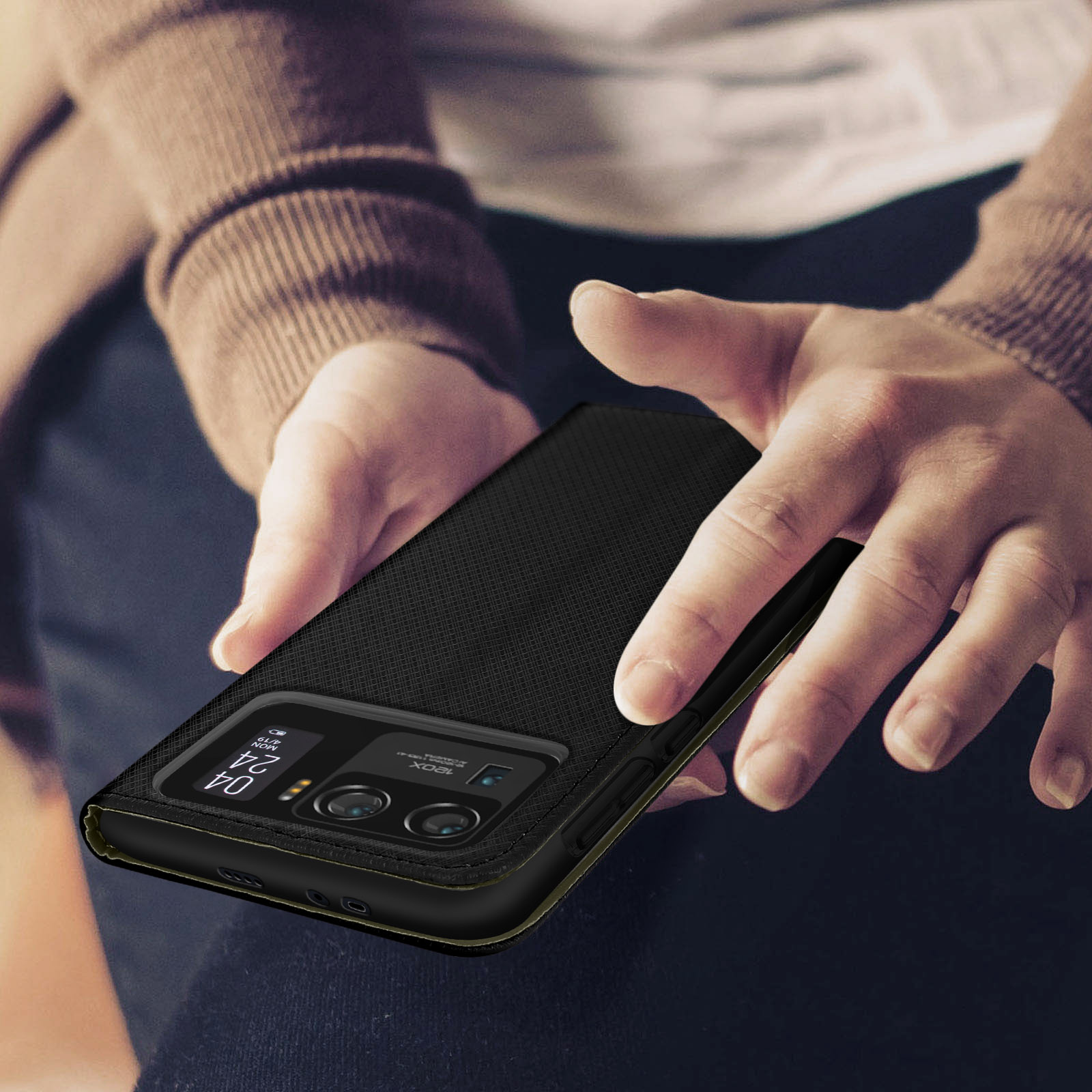 Una mano che tiene una custodia nera per telefono. Il telefono è nella custodia e ha una fotocamera.