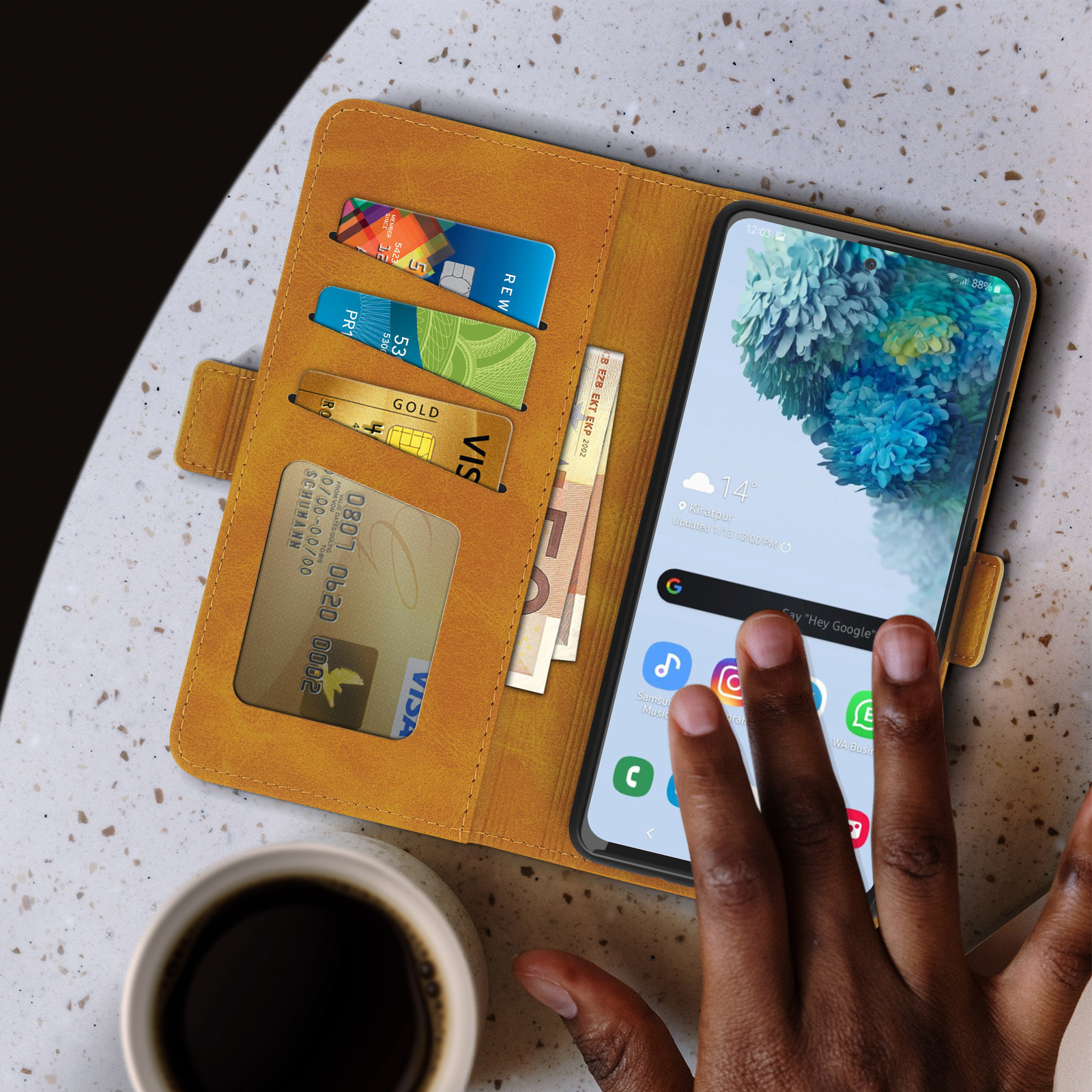 Téléphone dans un étui portefeuille jaune. Cartes et argent visibles. Tasse de café.