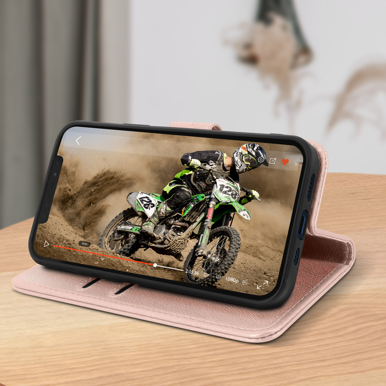 Un telefono in una custodia rosa che riproduce un video di una gara di motocross su un tavolo di legno.
