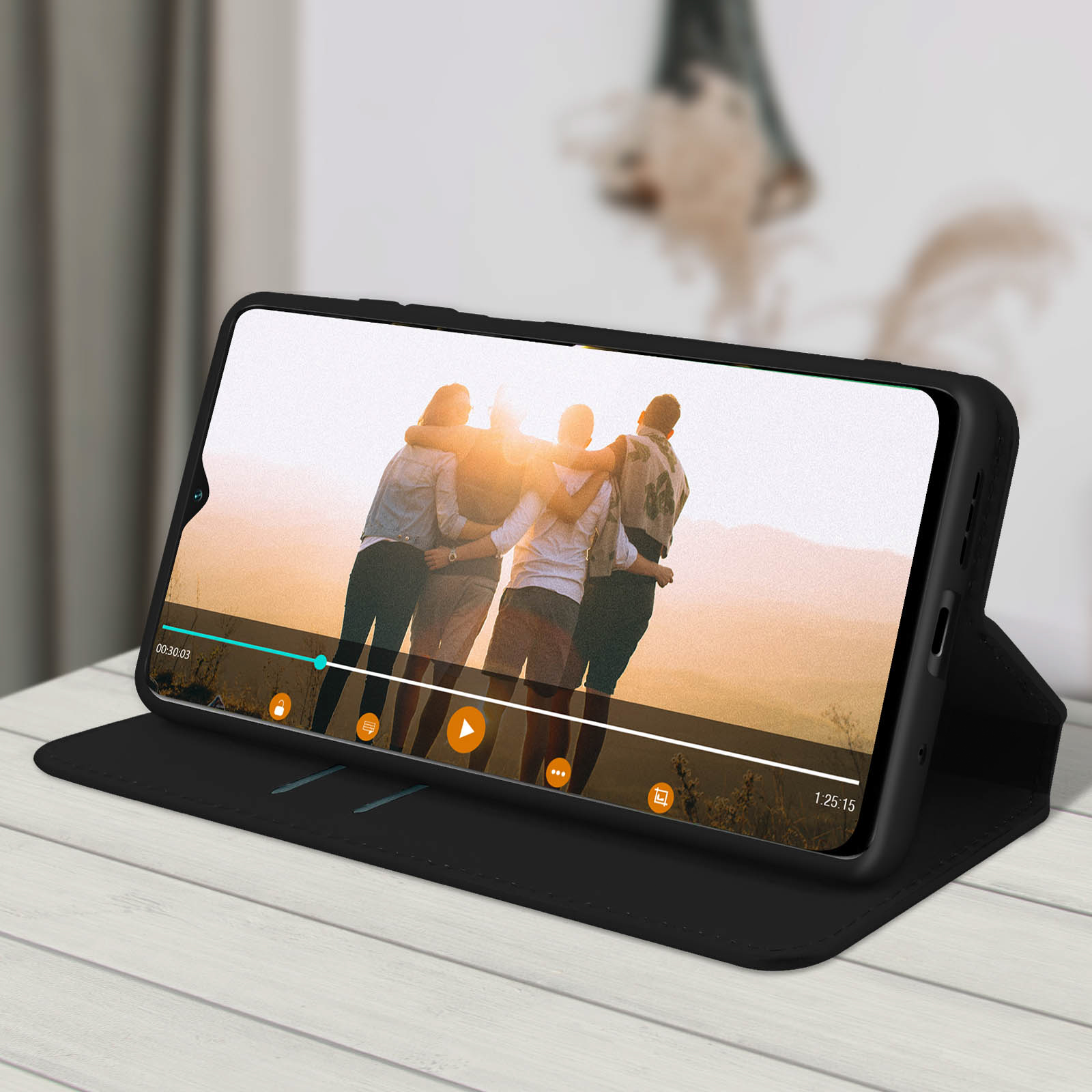 Telefono in custodia nera, mostra video di persone che si abbracciano. Custodia su tavolo di legno.