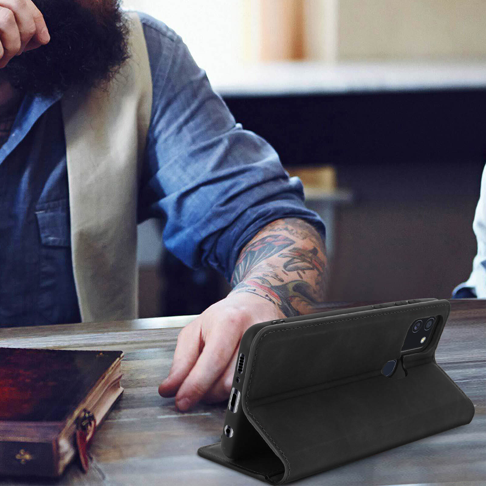 Un uomo con la barba è seduto e utilizza una custodia nera per telefono.