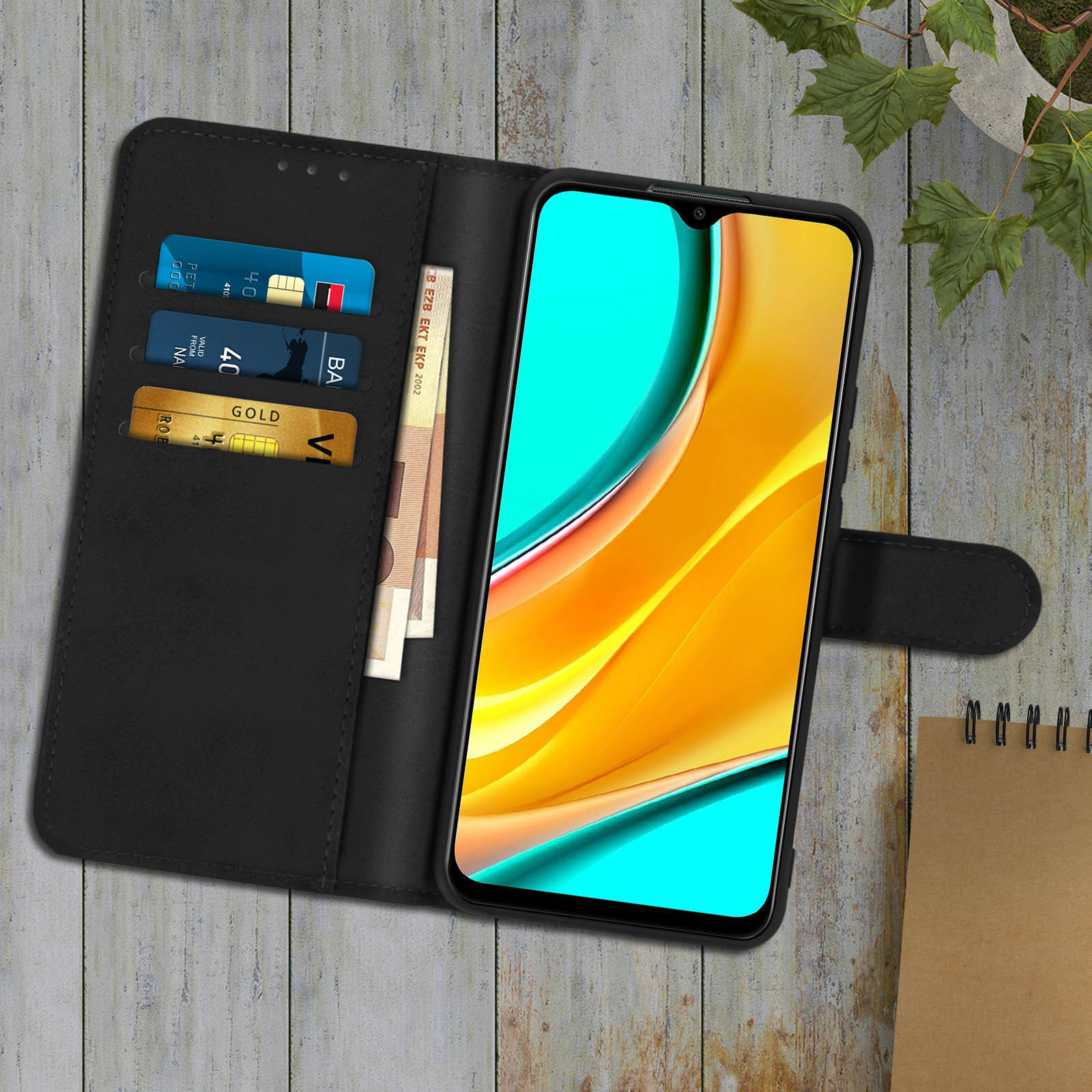 Una custodia per telefono nera aperta con un telefono che mostra uno schermo colorato. Carte di credito e denaro sono nella custodia.