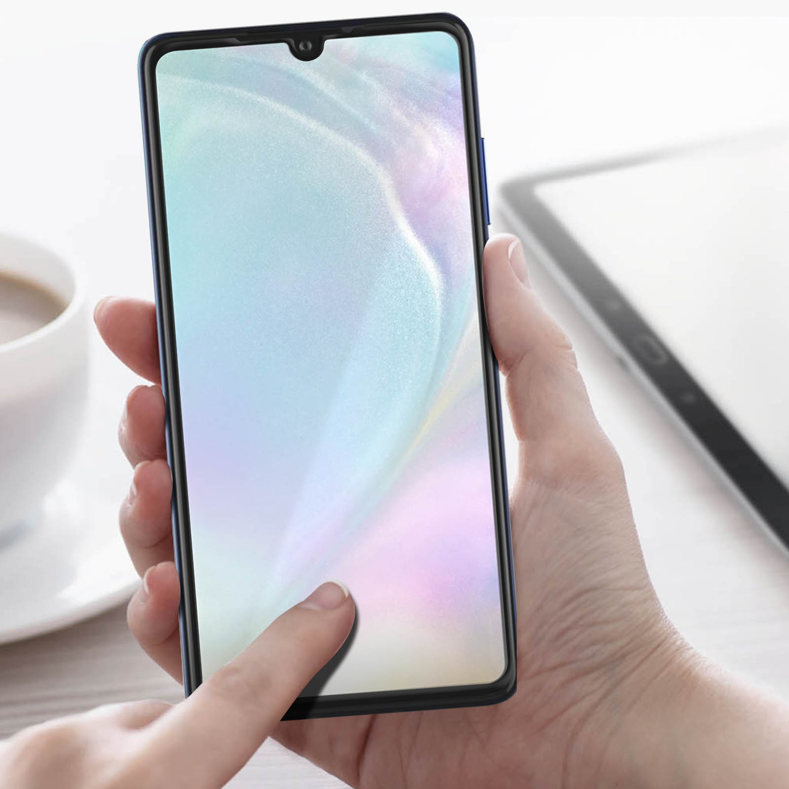 Mano che tiene uno smartphone, applicando una protezione schermo. Tavolo bianco sullo sfondo.