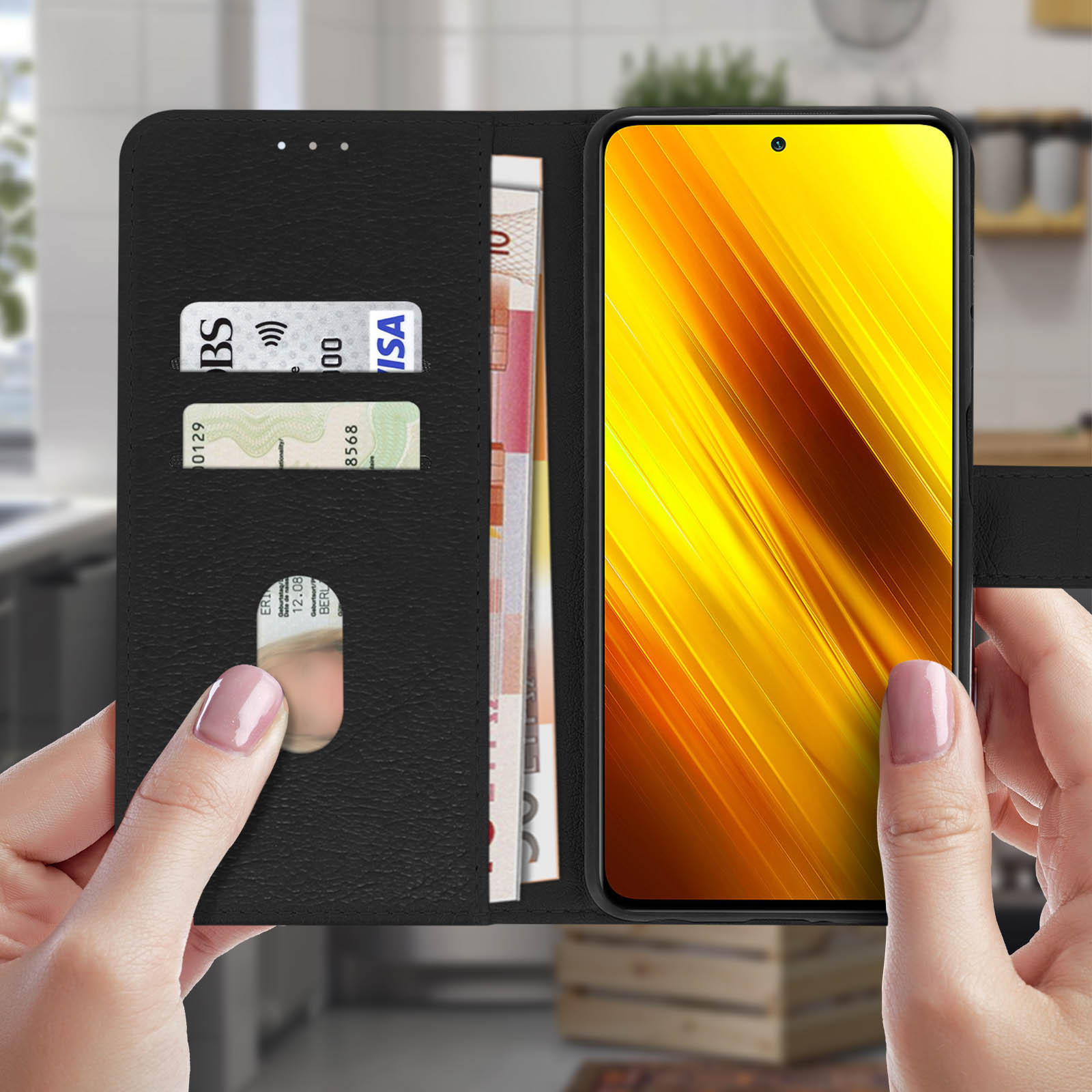Custodia nera per telefono aperta, che rivela un telefono con schermo giallo, carte e denaro. Mani.
