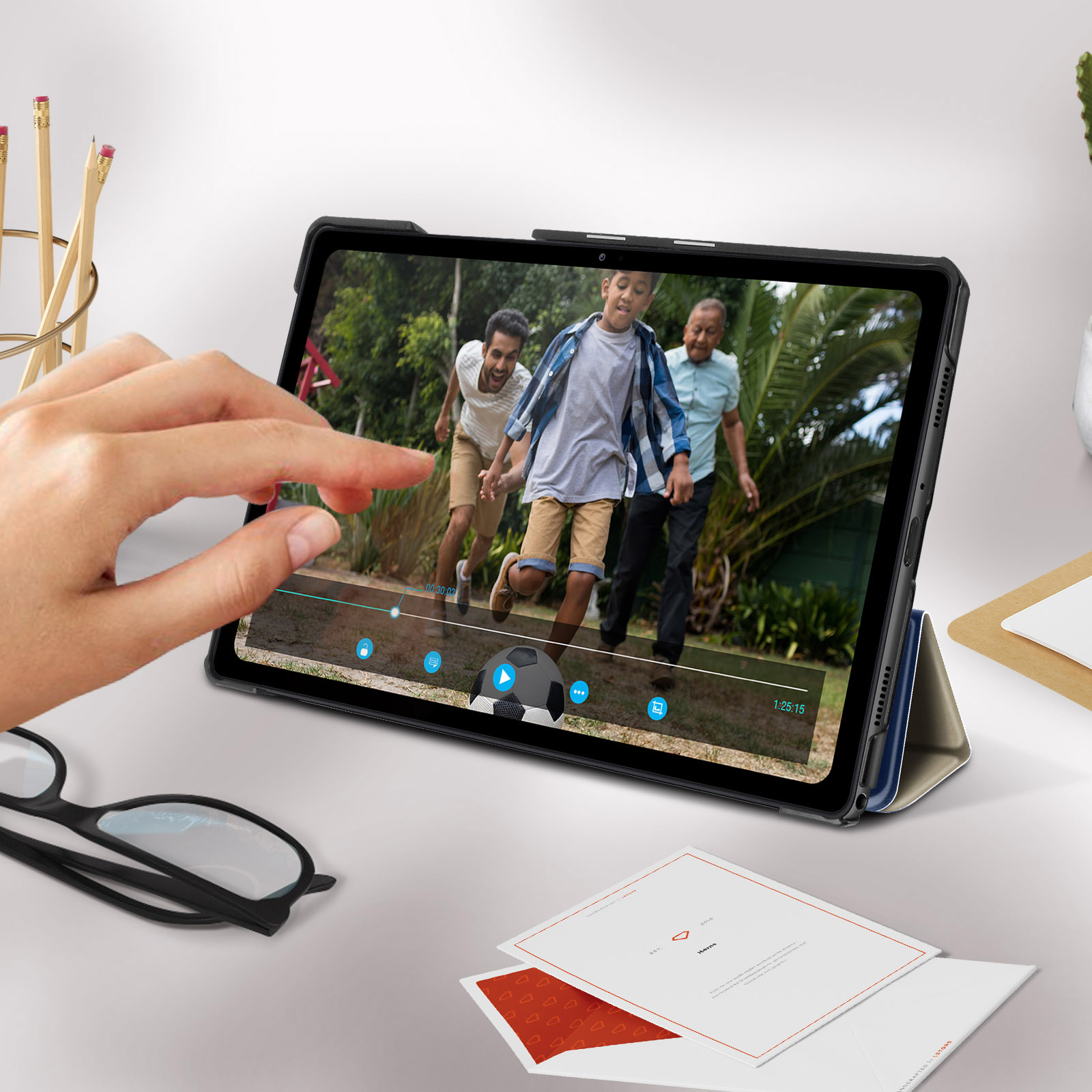 Una mano che tocca lo schermo di un tablet che riproduce un video di persone che giocano a calcio.