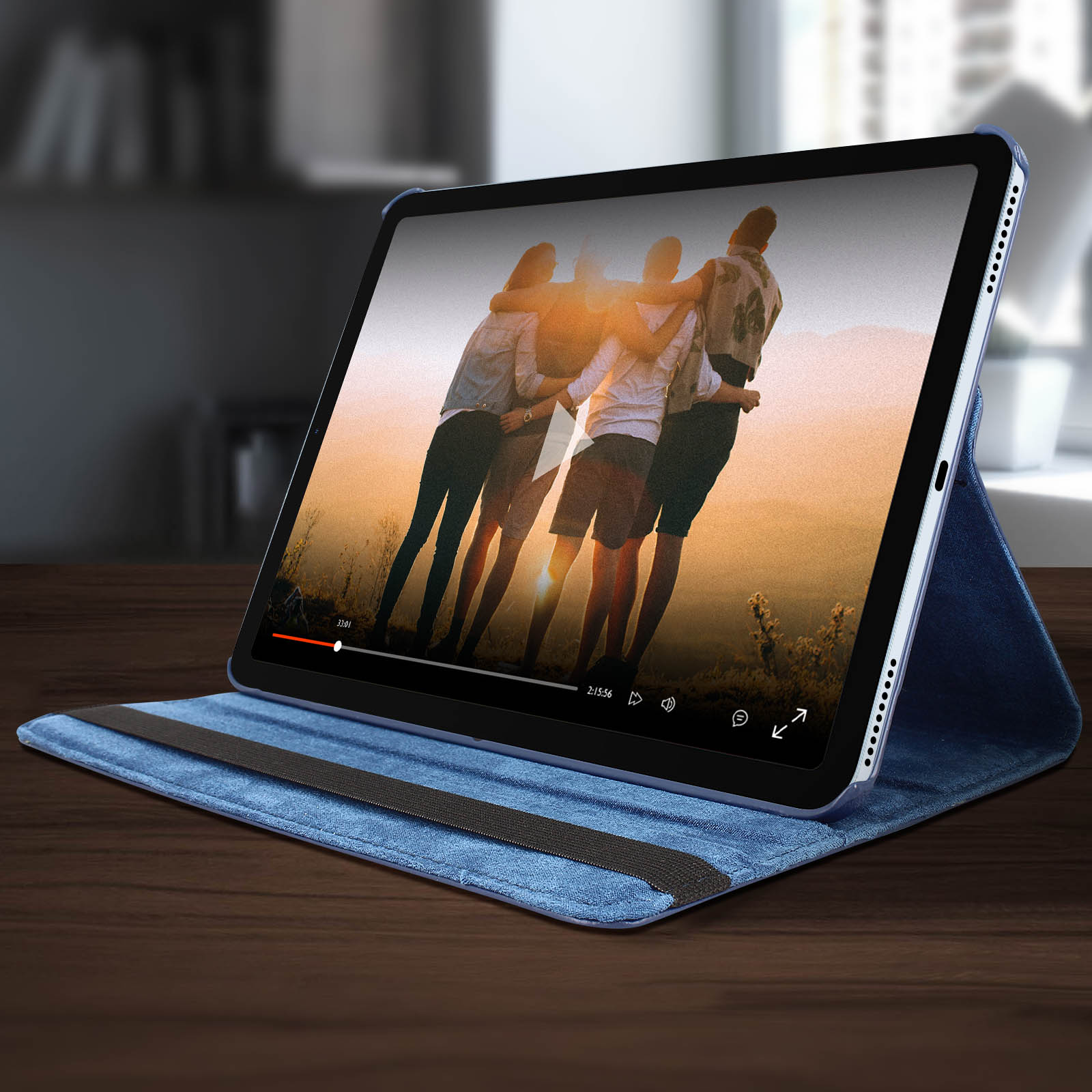 Un tablet mostra un video, in una custodia blu, su un tavolo di legno. Sfondo scuro.