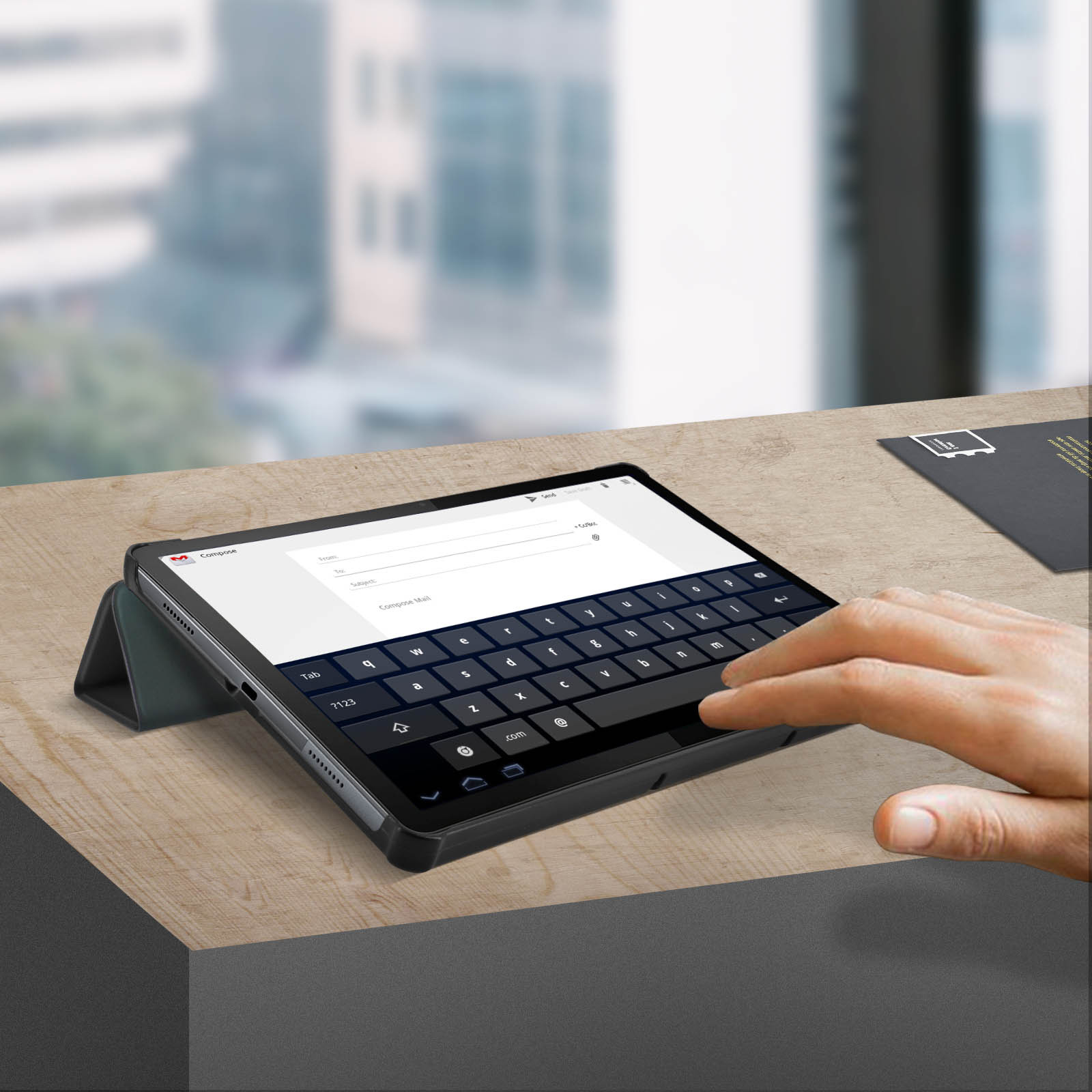 Una mano sta digitando sulla tastiera di un tablet. Un tablet nero è su un tavolo di legno. Una lettera è visibile.