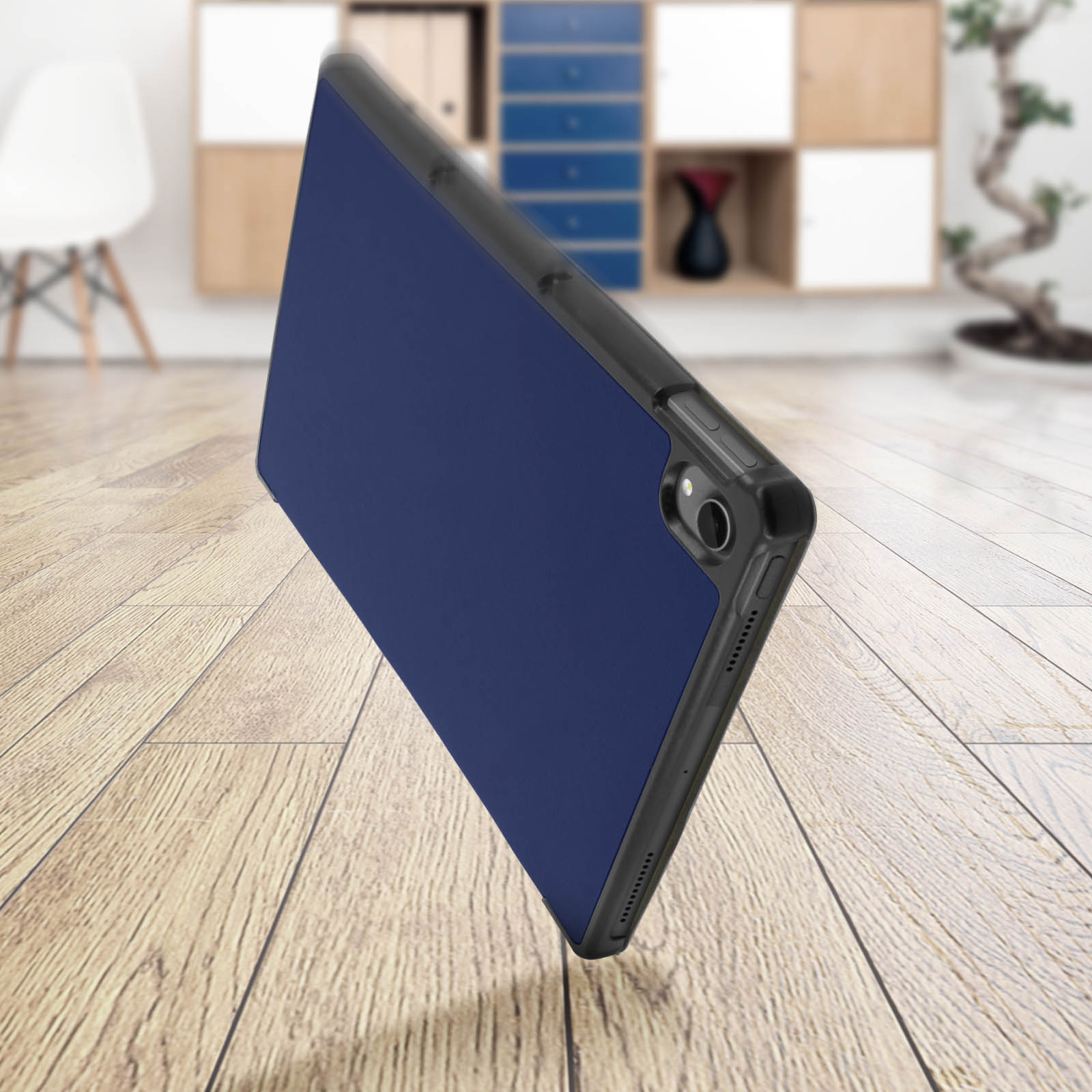 Un tablet in una custodia blu scuro, appoggiato su una superficie in legno. Lo sfondo include un ambiente stanza.