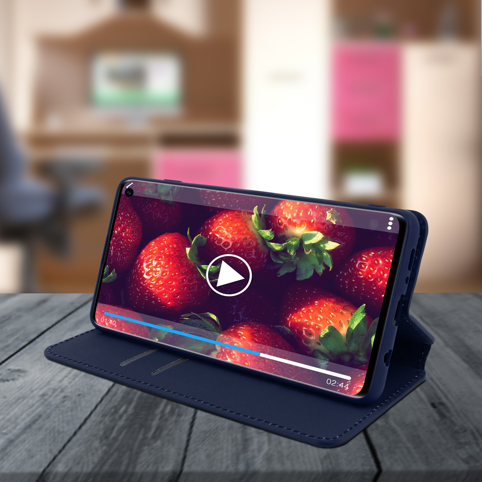 Telefono che mostra video di fragole. Telefono in una custodia di pelle blu, su un tavolo di legno.