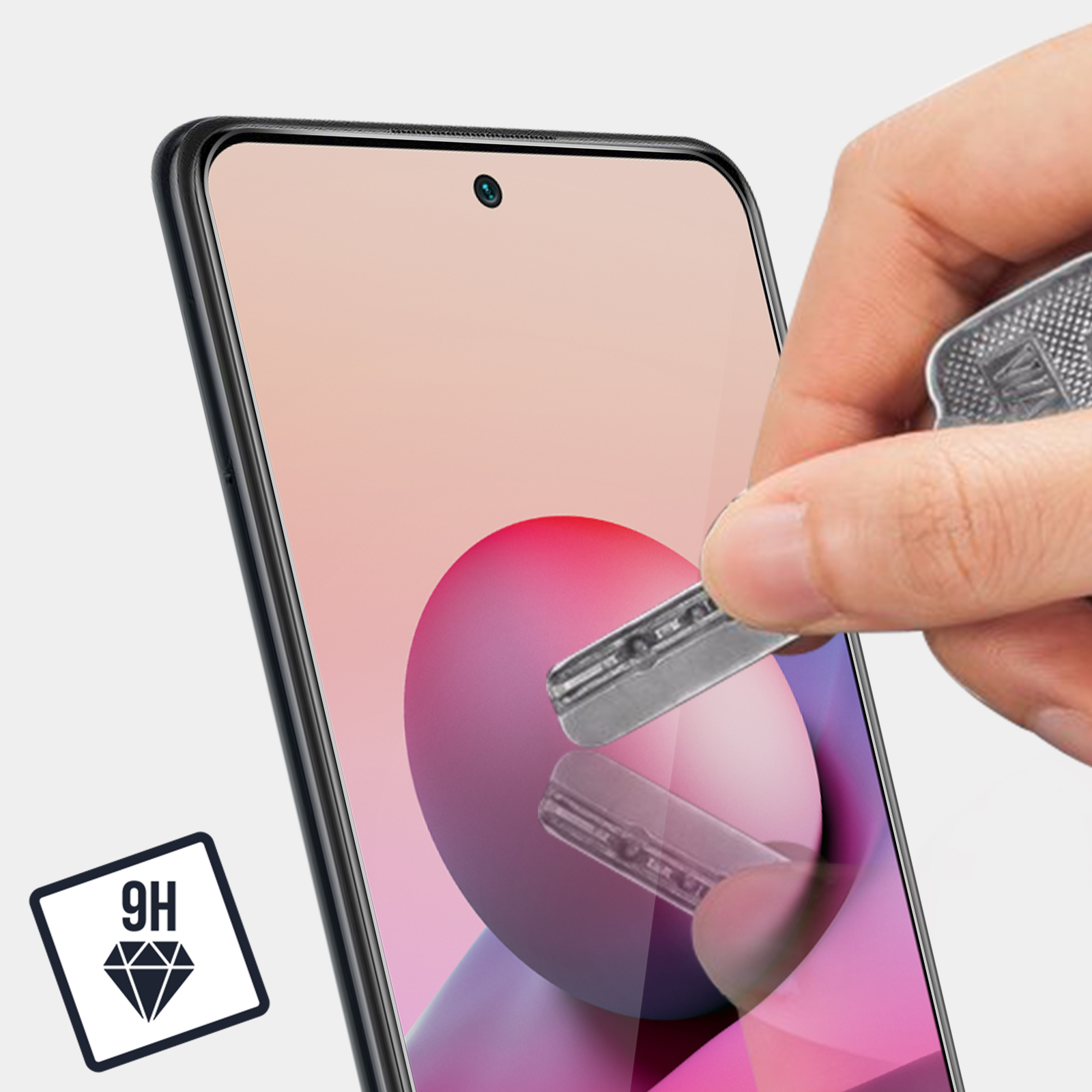 Una persona applica una protezione per lo schermo a un telefono. Un'icona diamante 9H è visibile.