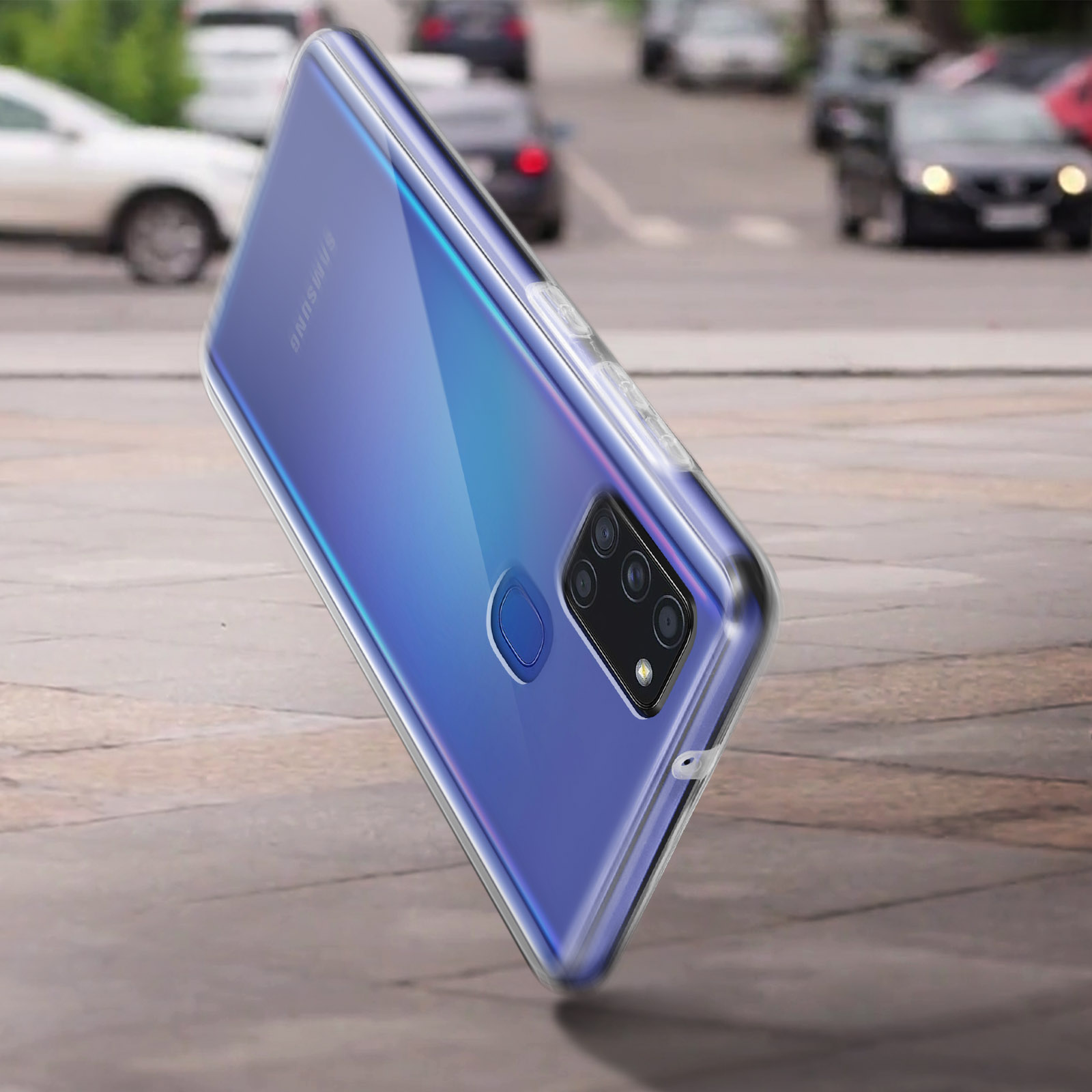 Un telefono in una custodia trasparente, posto su una strada, con auto sfocate sullo sfondo.