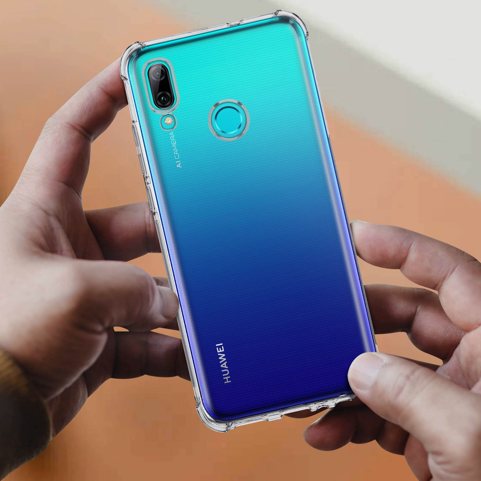 Una custodia trasparente per telefono con una sfumatura blu e verde. Il telefono è tenuto da due mani.