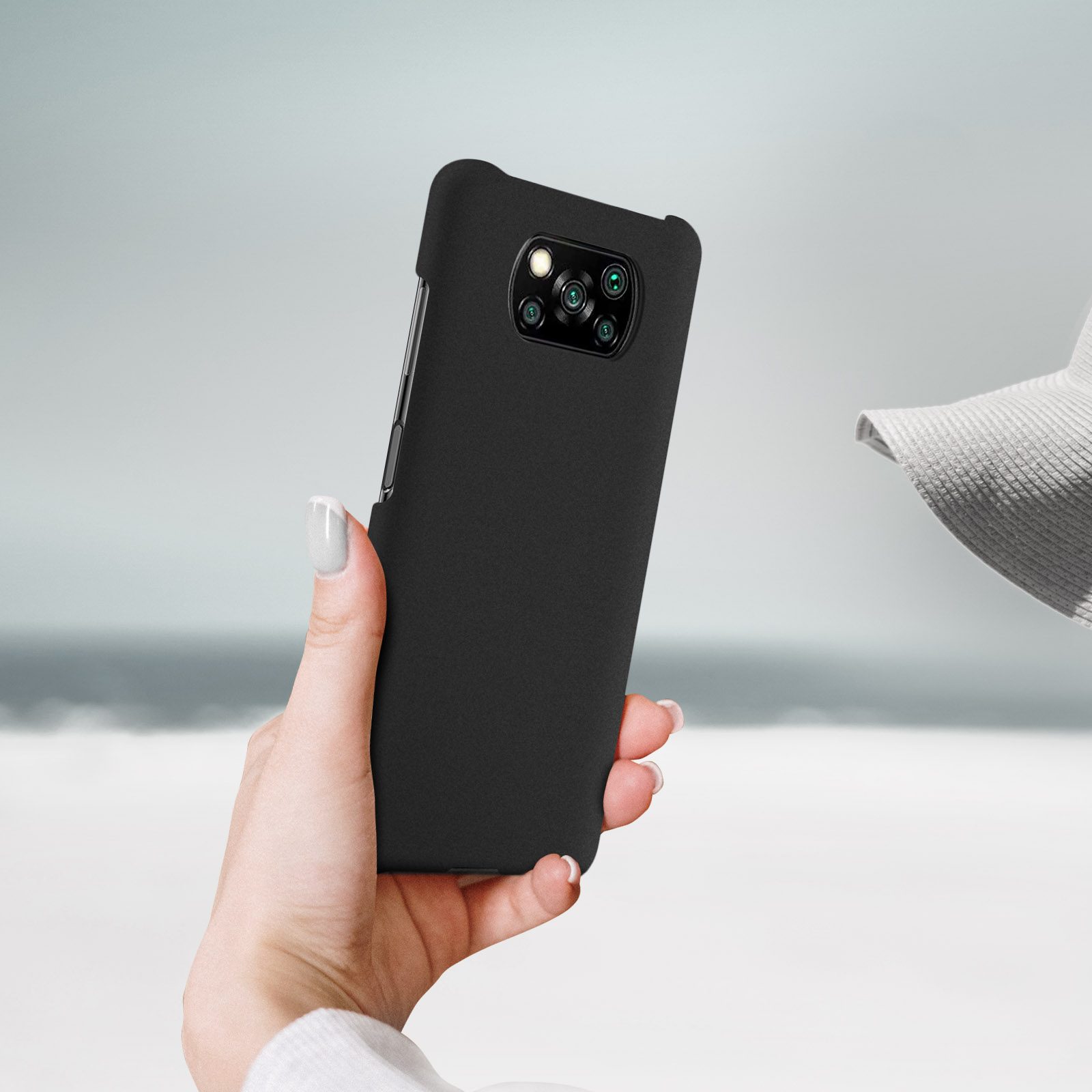 Eine Frau hält ein schwarzes Telefon mit Hülle. Die Hülle bedeckt Rückseite und Seiten des Telefons.
