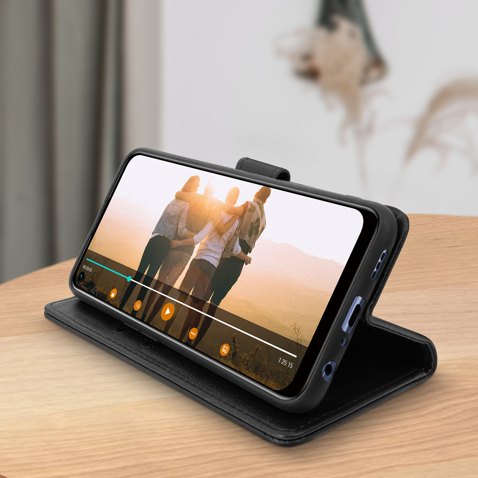 Téléphone dans un étui noir, affichant une vidéo de personnes. Le téléphone repose sur une surface en bois.