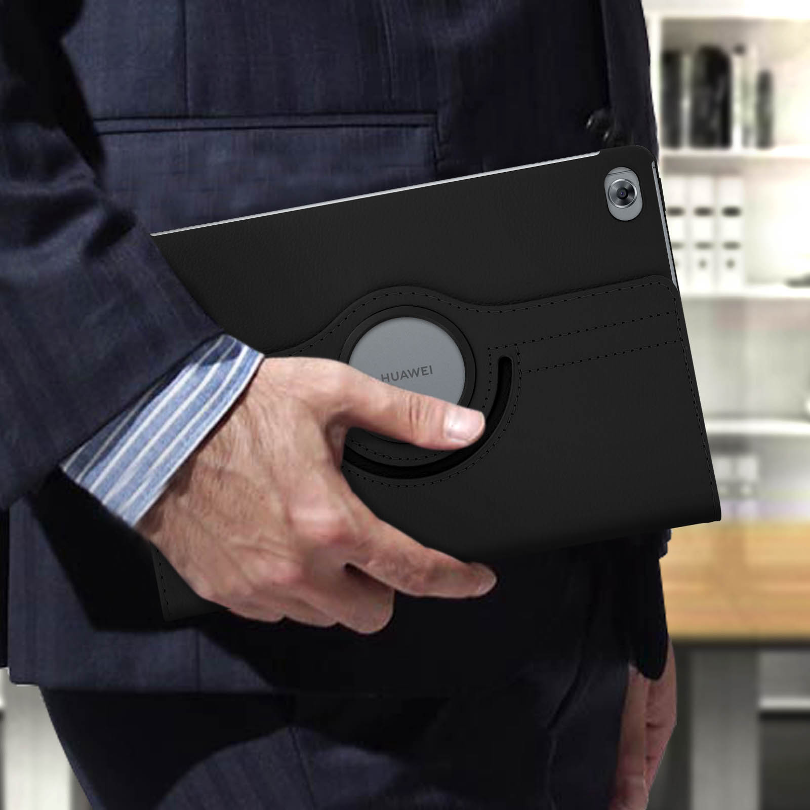 Una persona che tiene in mano un tablet nero in una custodia nera. Lo sfondo è un ufficio.