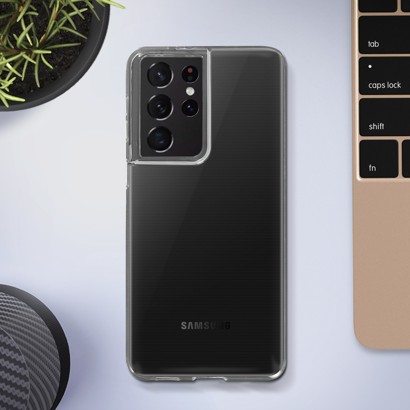Une coque de téléphone transparente sur un téléphone noir. C'est sur un bureau à côté d'un clavier et d'une plante.