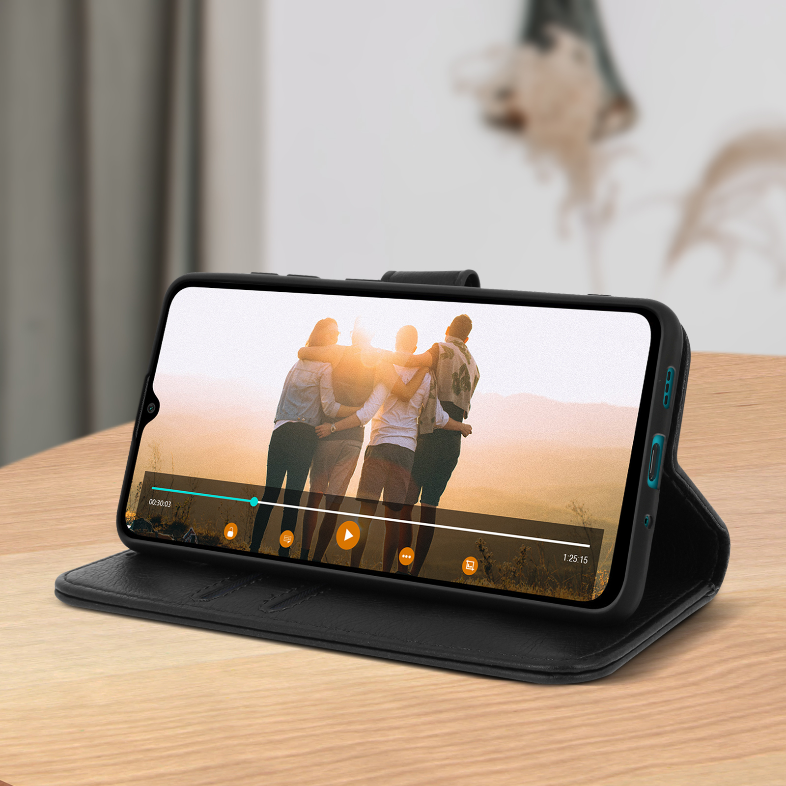Téléphone dans un étui noir affichant une vidéo de personnes s'embrassant. Sur une table en bois.