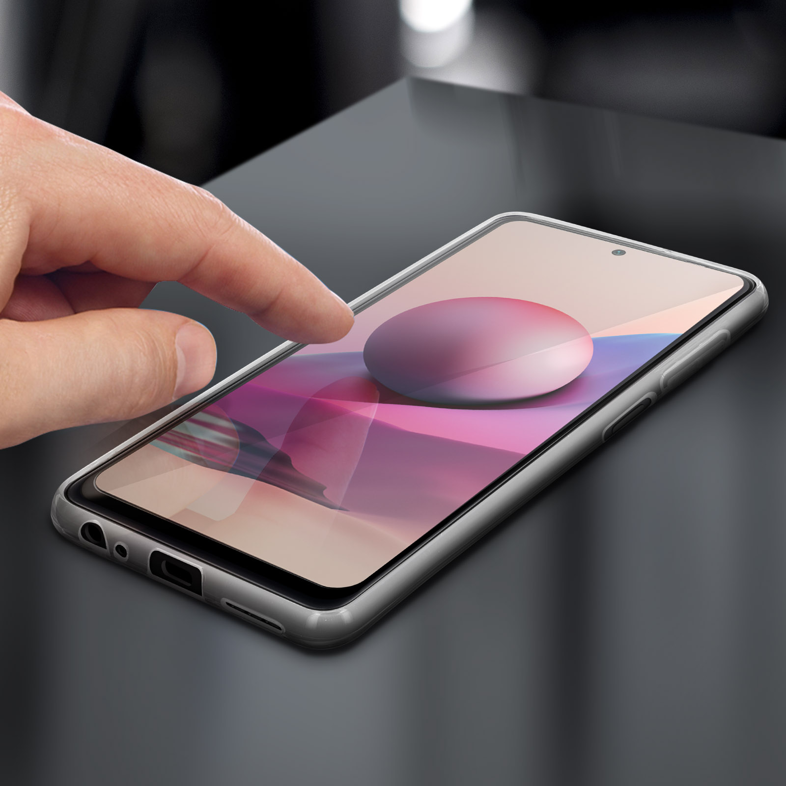 Mano che tocca lo schermo del telefono. Lo schermo mostra un design viola e rosa. Tavolo scuro.