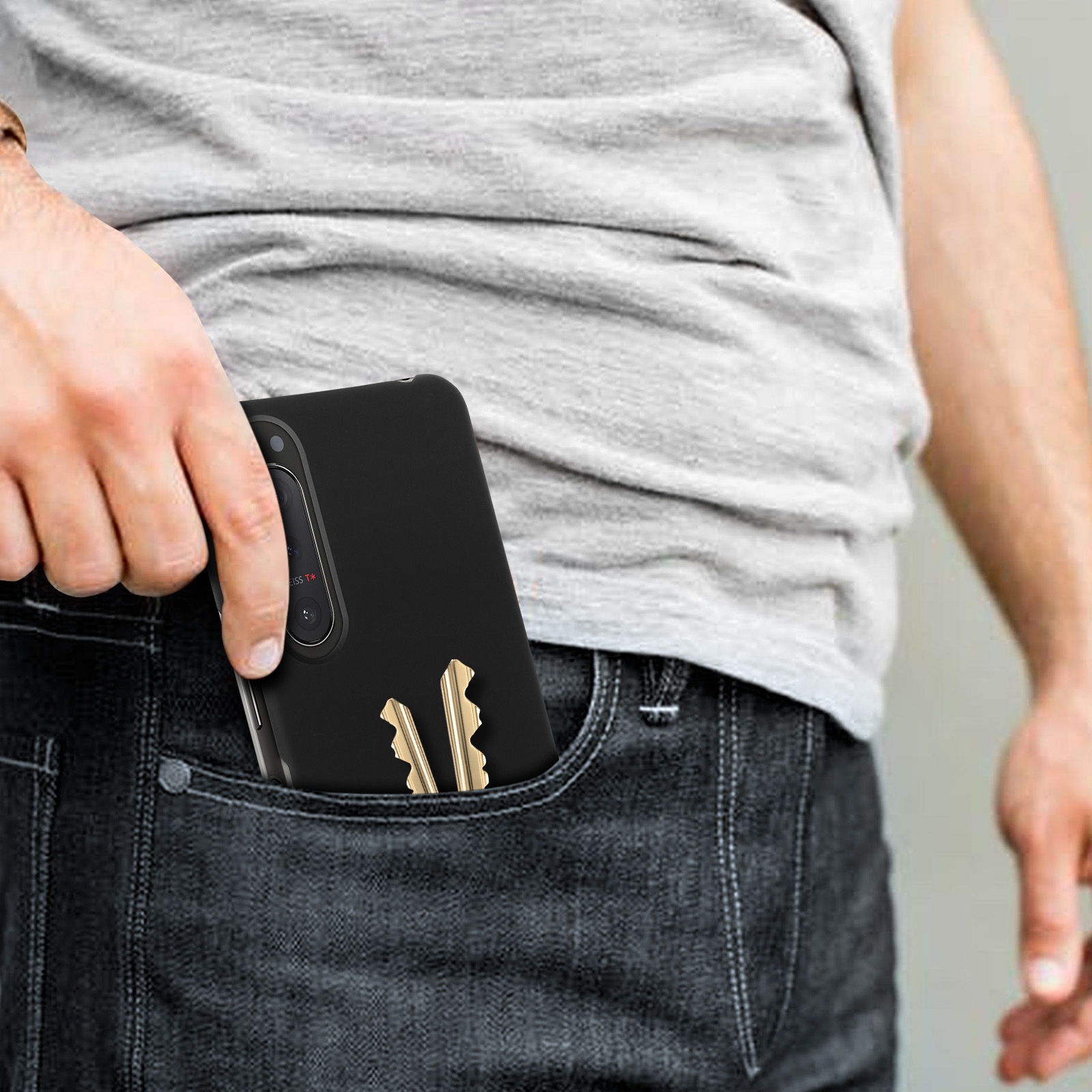 La mano di una persona con un telefono in tasca con le chiavi. Custodia e chiavi sono visibili.