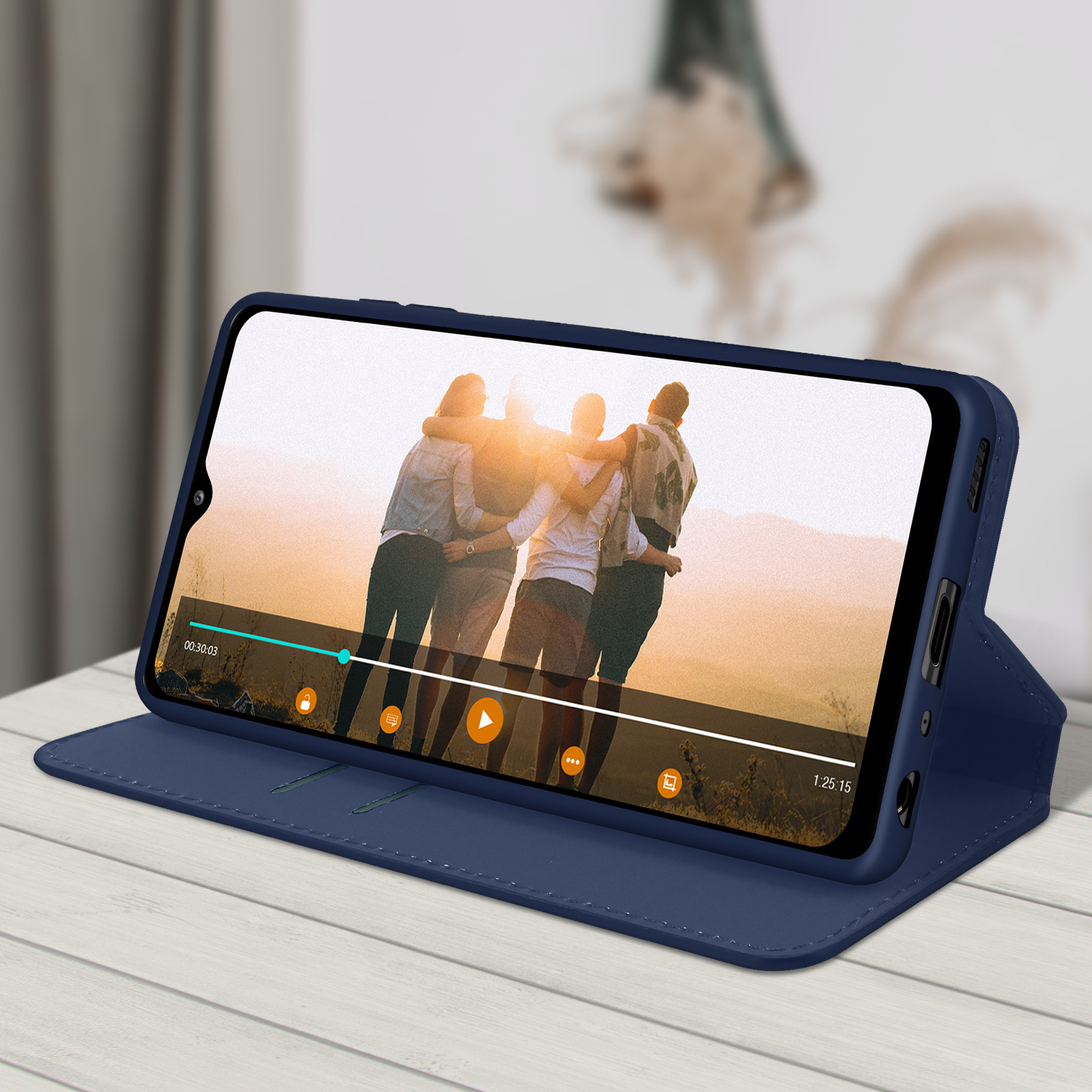 Téléphone dans étui bleu montrant une vidéo. Table en bois, fond flou.