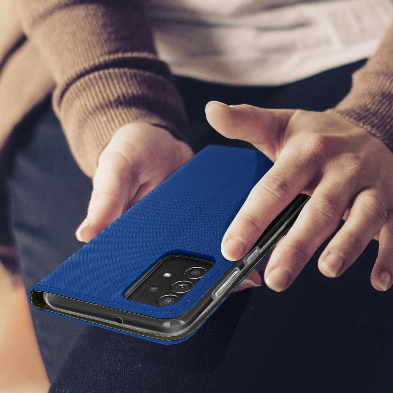 Blaue Handyhülle, von einer Person gehalten. Die Hülle ist geöffnet. Das Telefon ist sichtbar.