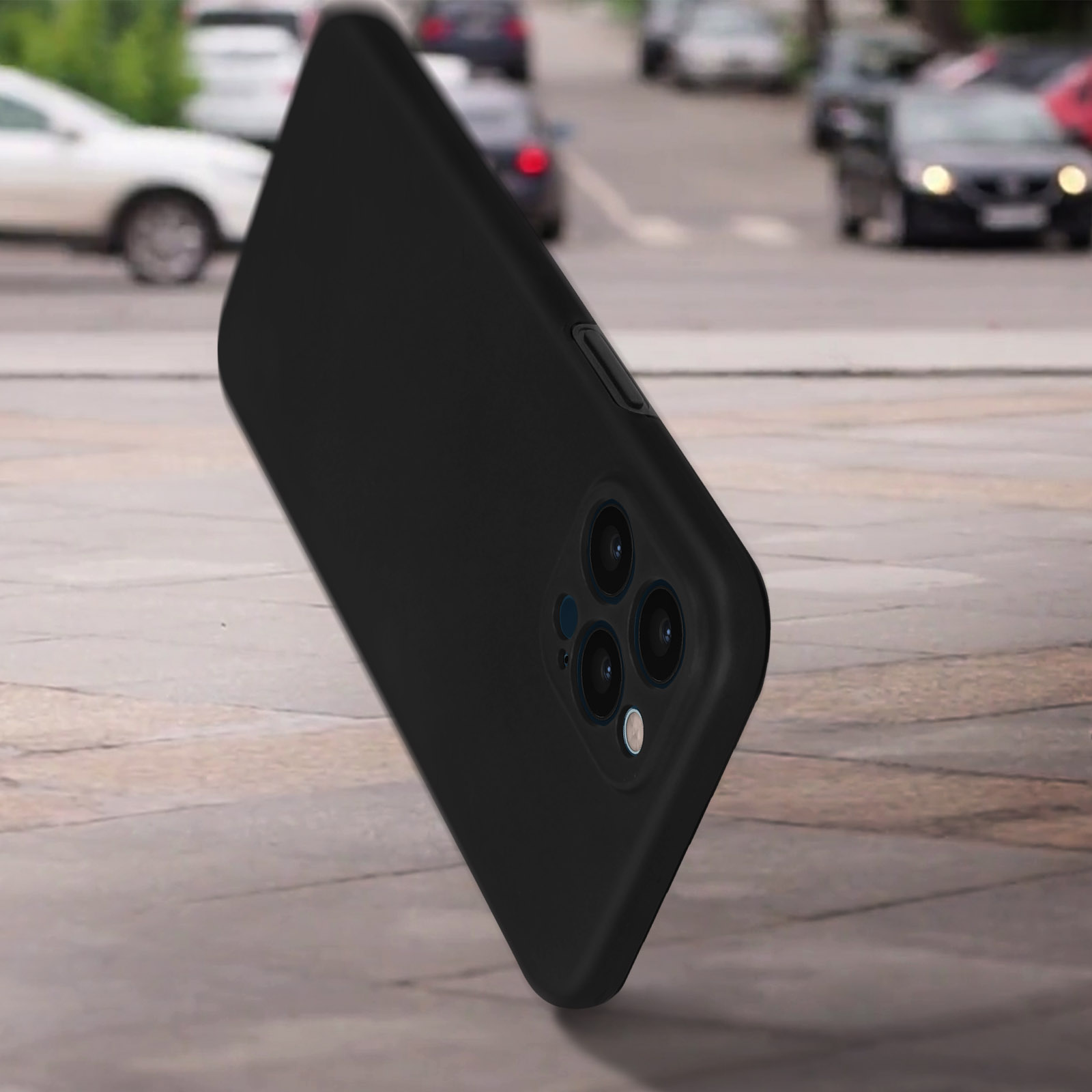 Zwarte telefoon met drie camera's op een grijze ondergrond. Auto's in de vage achtergrond.