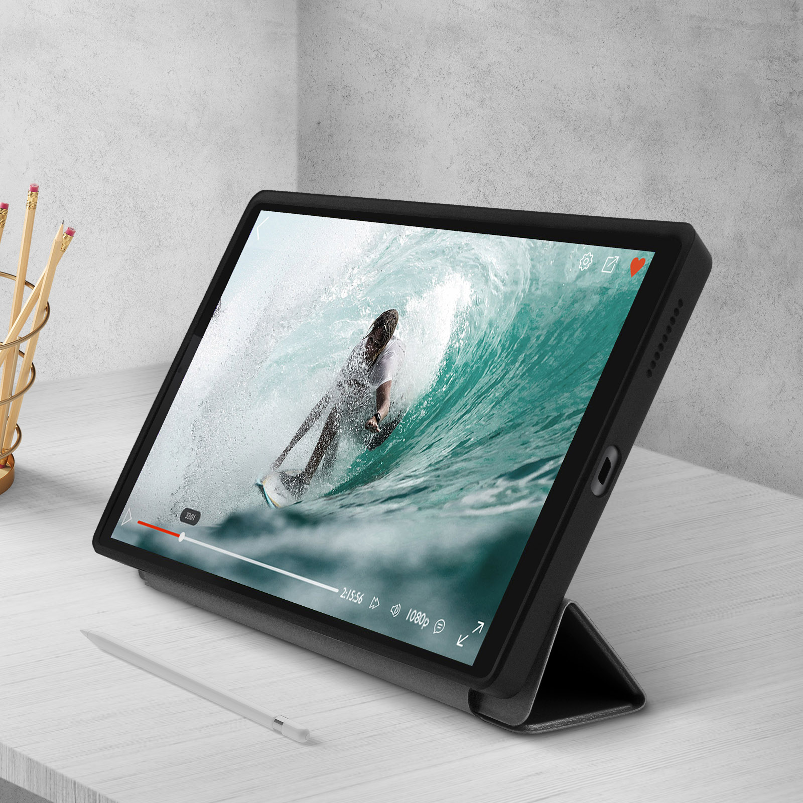 Tablet con un video di un surfista sullo schermo, inserito in una custodia nera su un tavolo.